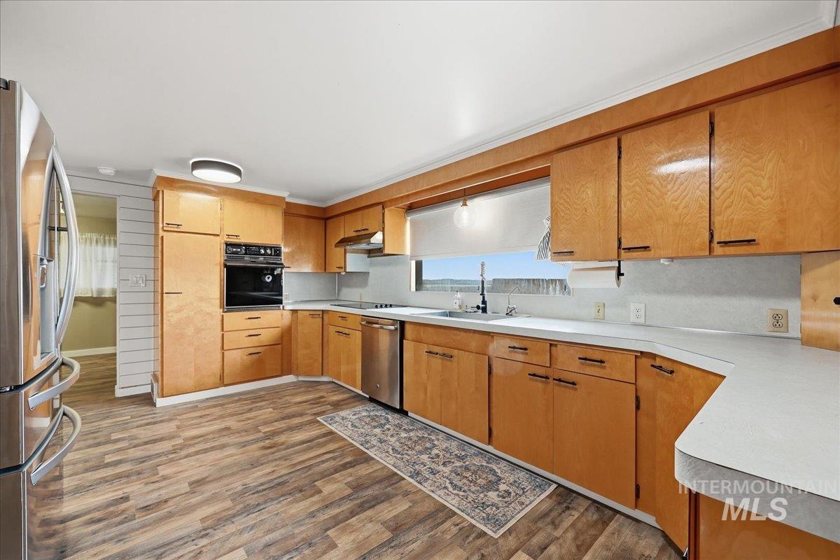 Kitchen with black appliances, light countertops, dark wood-style floors, and brown cabinets