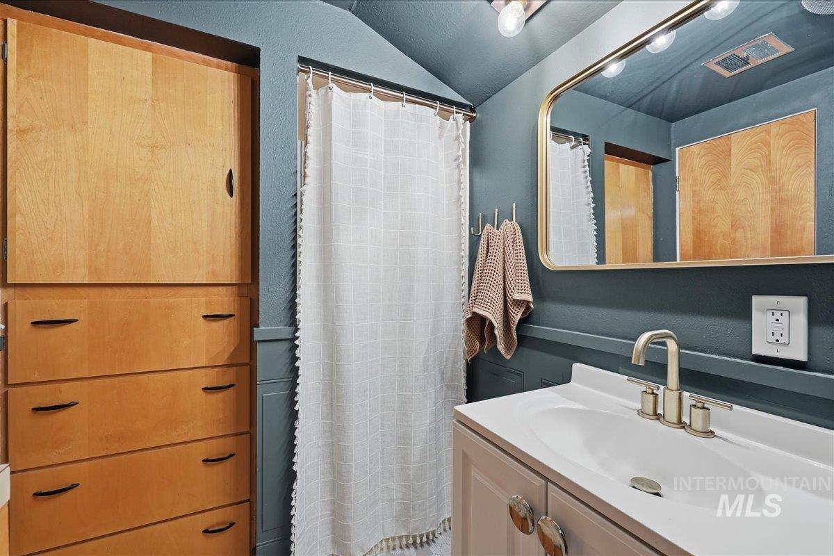 Bathroom featuring vanity, a shower with curtain, and vaulted ceiling