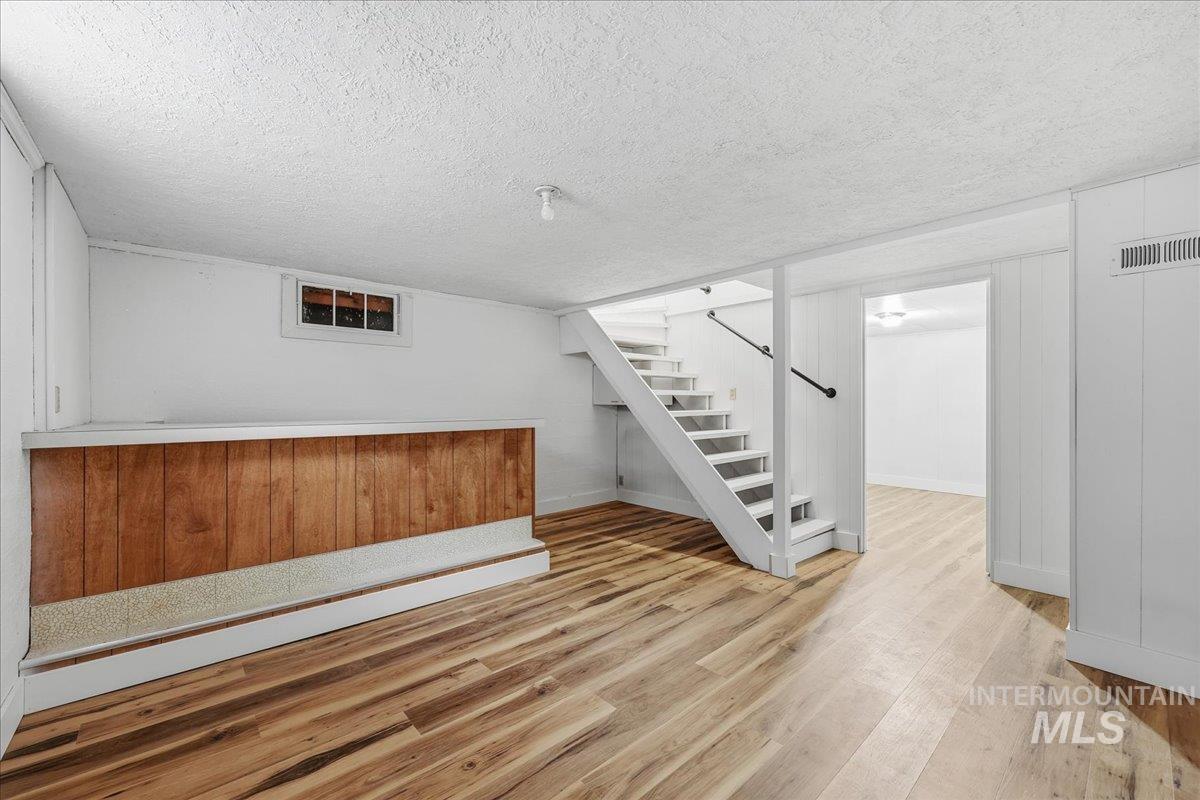 Bar featuring light wood finished floors, a textured ceiling, and stairs
