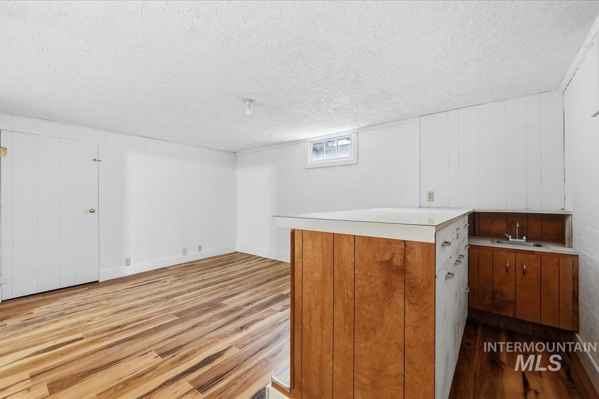 Bar area with light countertops, dark wood-style flooring, a textured ceiling, and brown cabinets