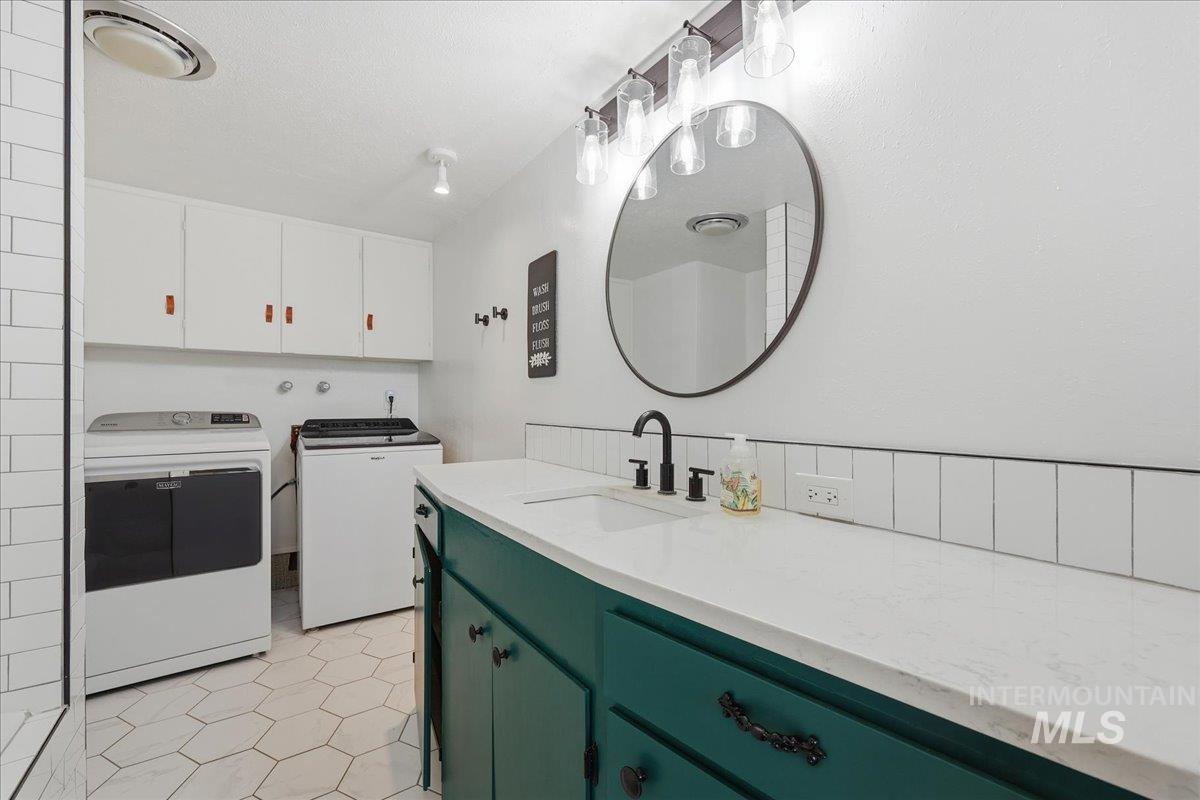 Washroom featuring cabinet space, light tile patterned floors, and washer and clothes dryer