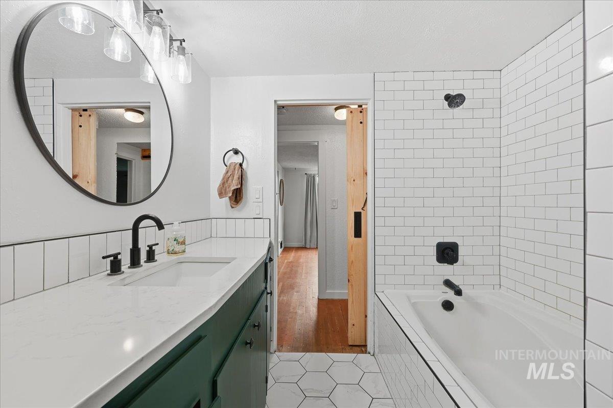 Full bathroom with tiled shower / bath, vanity, a textured ceiling, and light tile patterned flooring