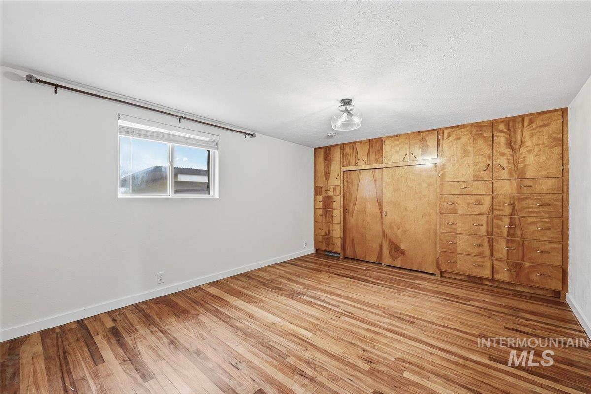 Unfurnished bedroom with a closet, a textured ceiling, and wood-type flooring