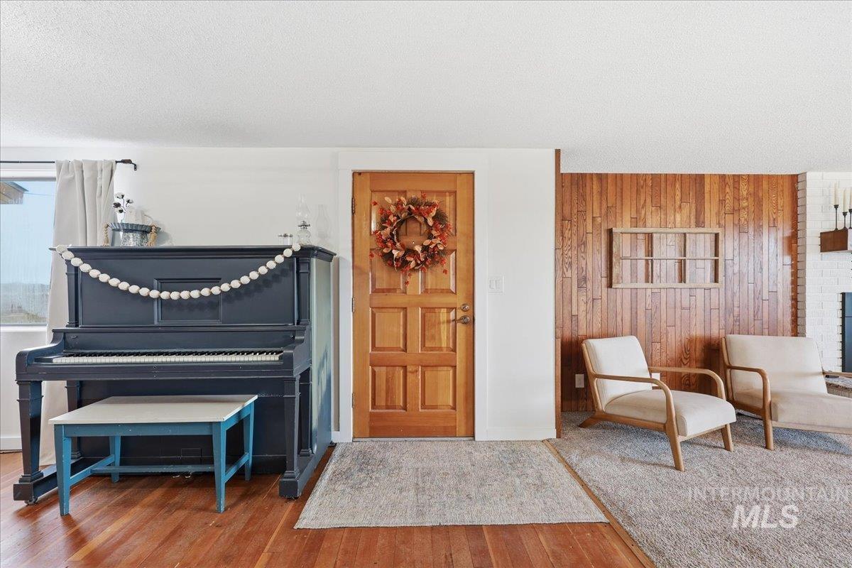 Living area featuring wood finished floors, wood walls, a textured ceiling, and a fireplace
