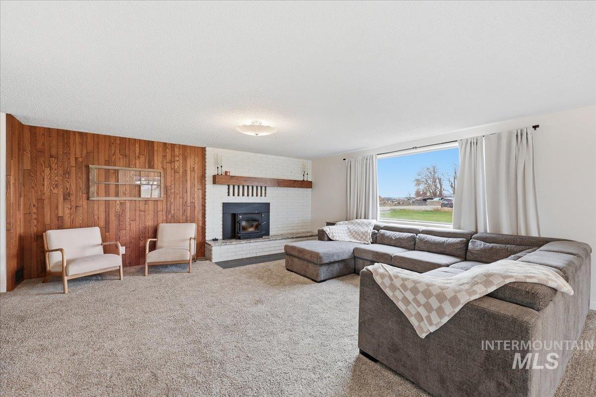 Living room with wooden walls, carpet floors, and a textured ceiling