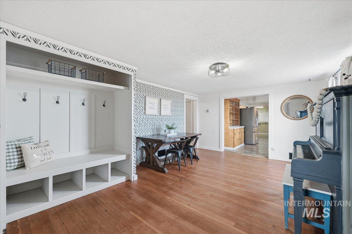 Mudroom featuring wallpapered walls, an accent wall, a textured ceiling, and light wood-style flooring