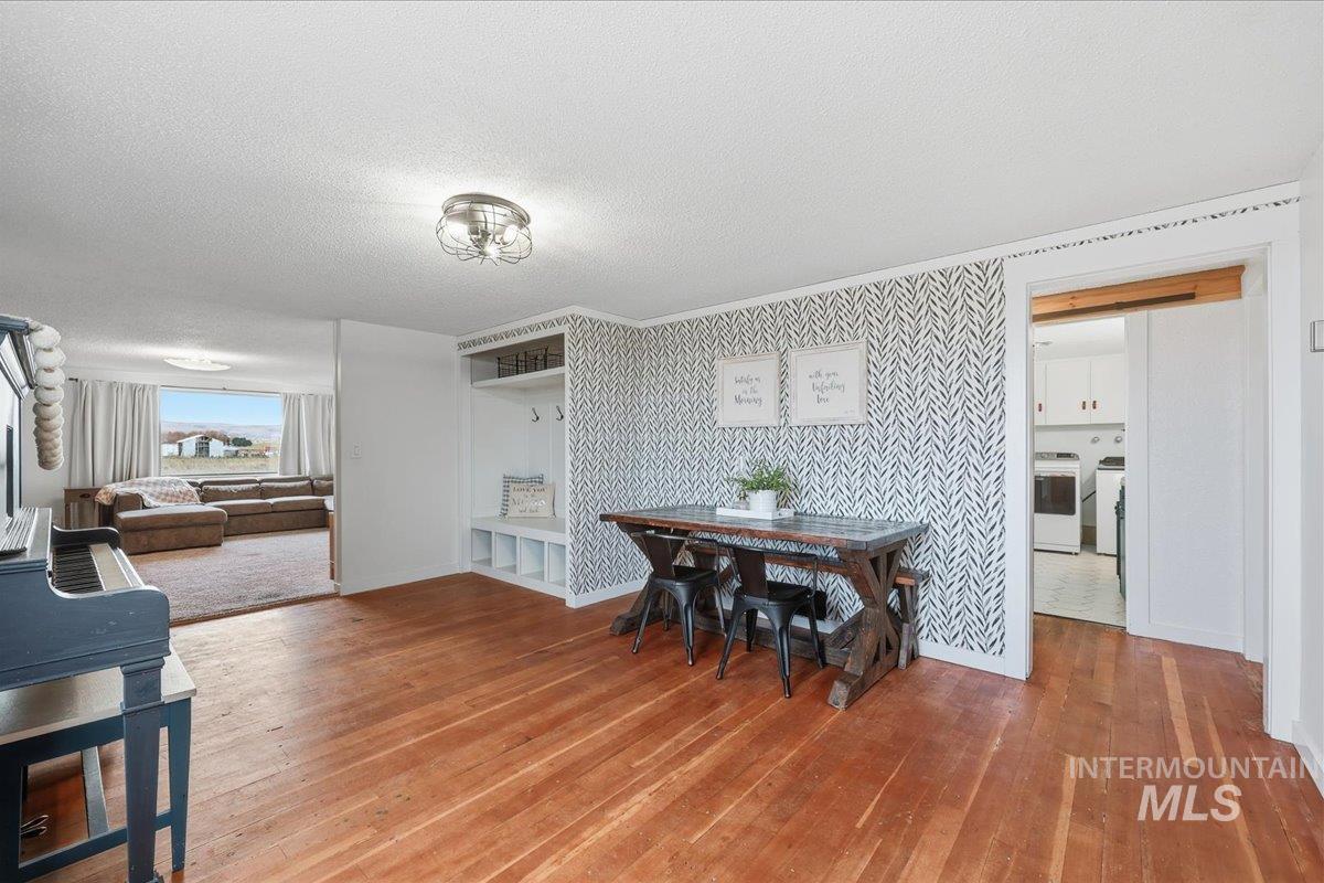 Dining space with wallpapered walls, a textured ceiling, light wood-style flooring, an accent wall, and washer and dryer