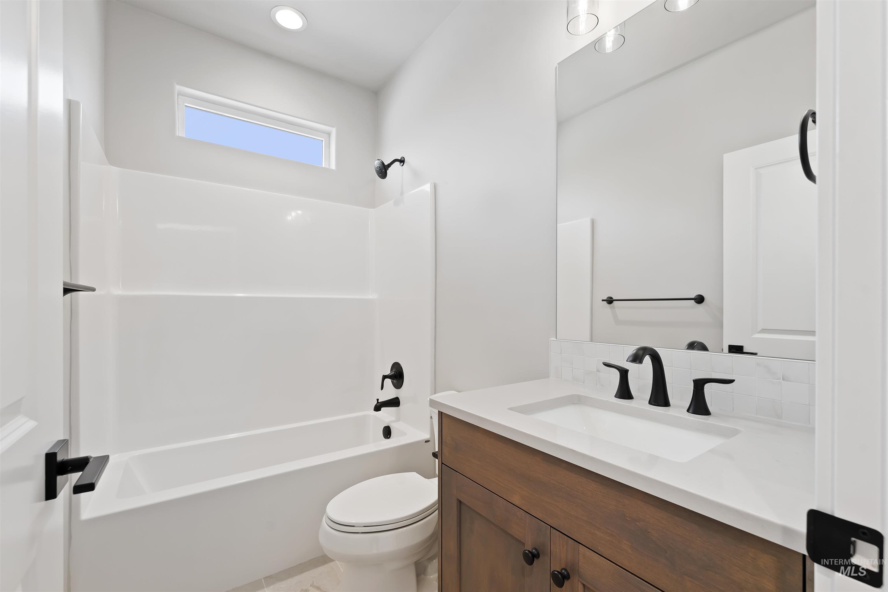 Bathroom with shower / tub combination, vanity, and decorative backsplash
