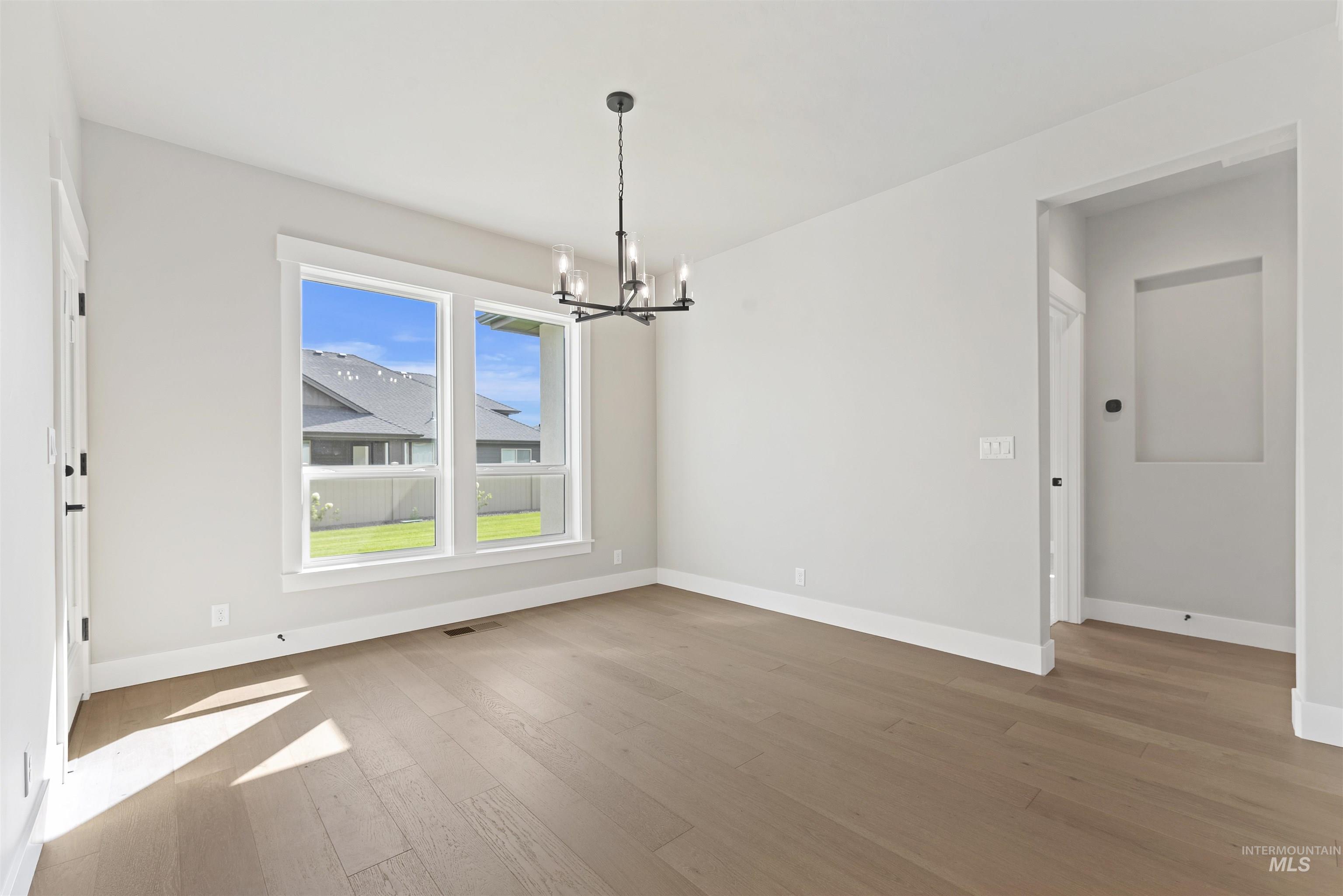 Unfurnished dining area featuring a chandelier and light wood-style floors