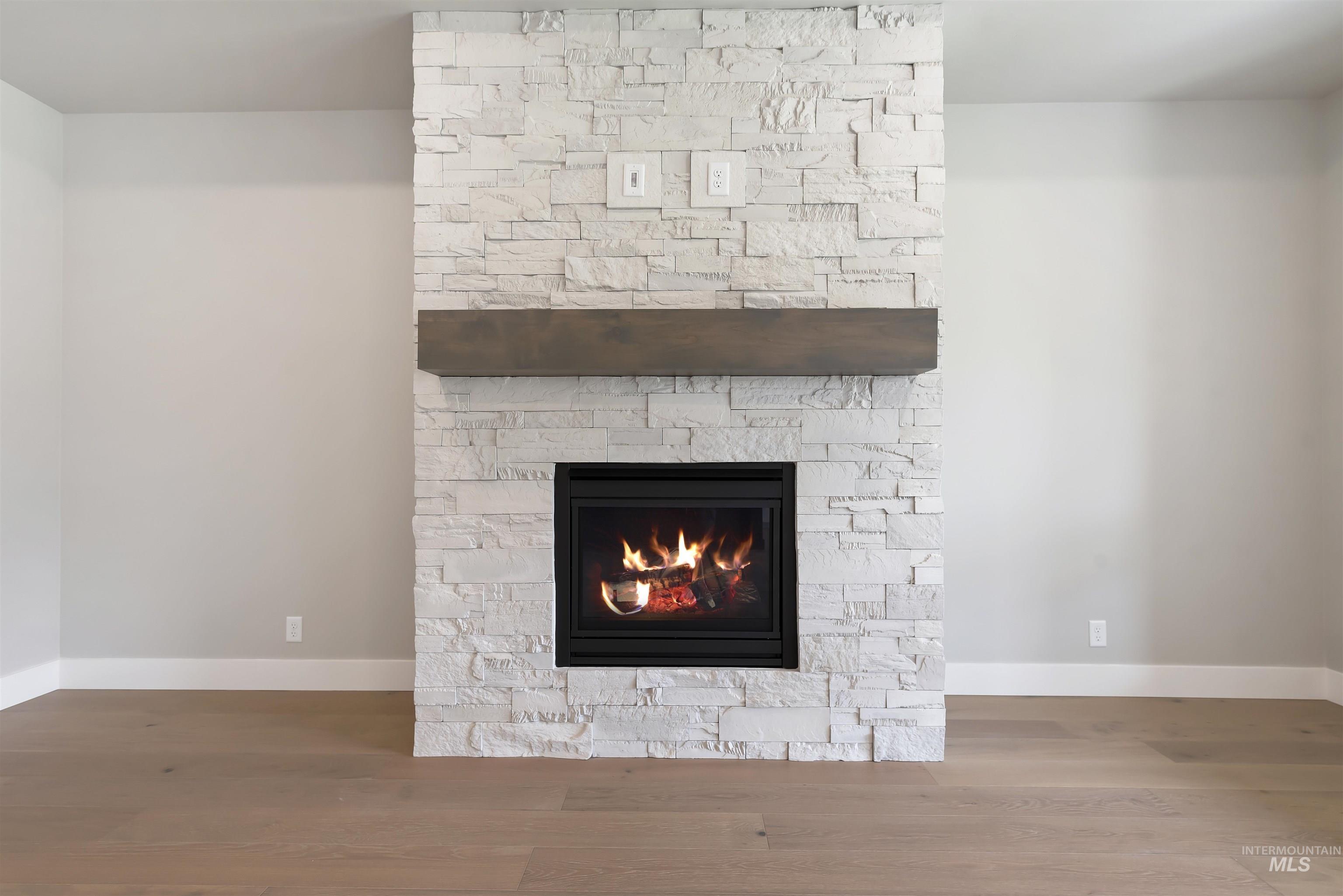 Detailed view of wood finished floors and a lit fireplace