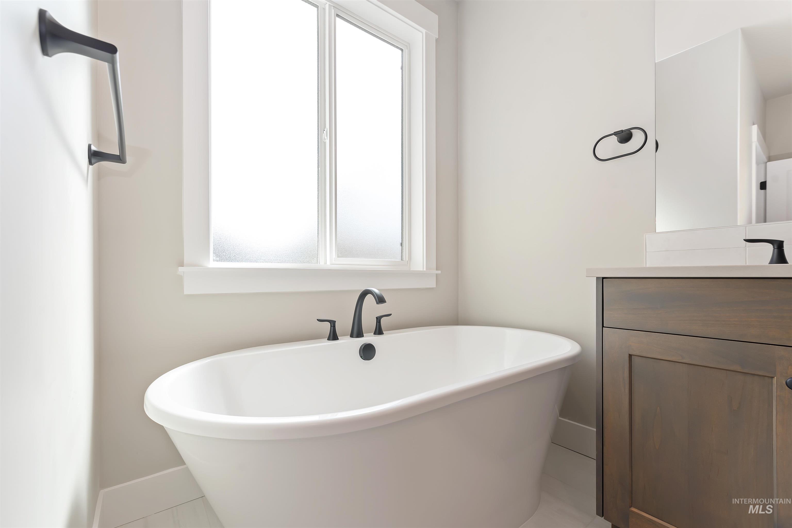Full bathroom with vanity, a soaking tub, and healthy amount of natural light