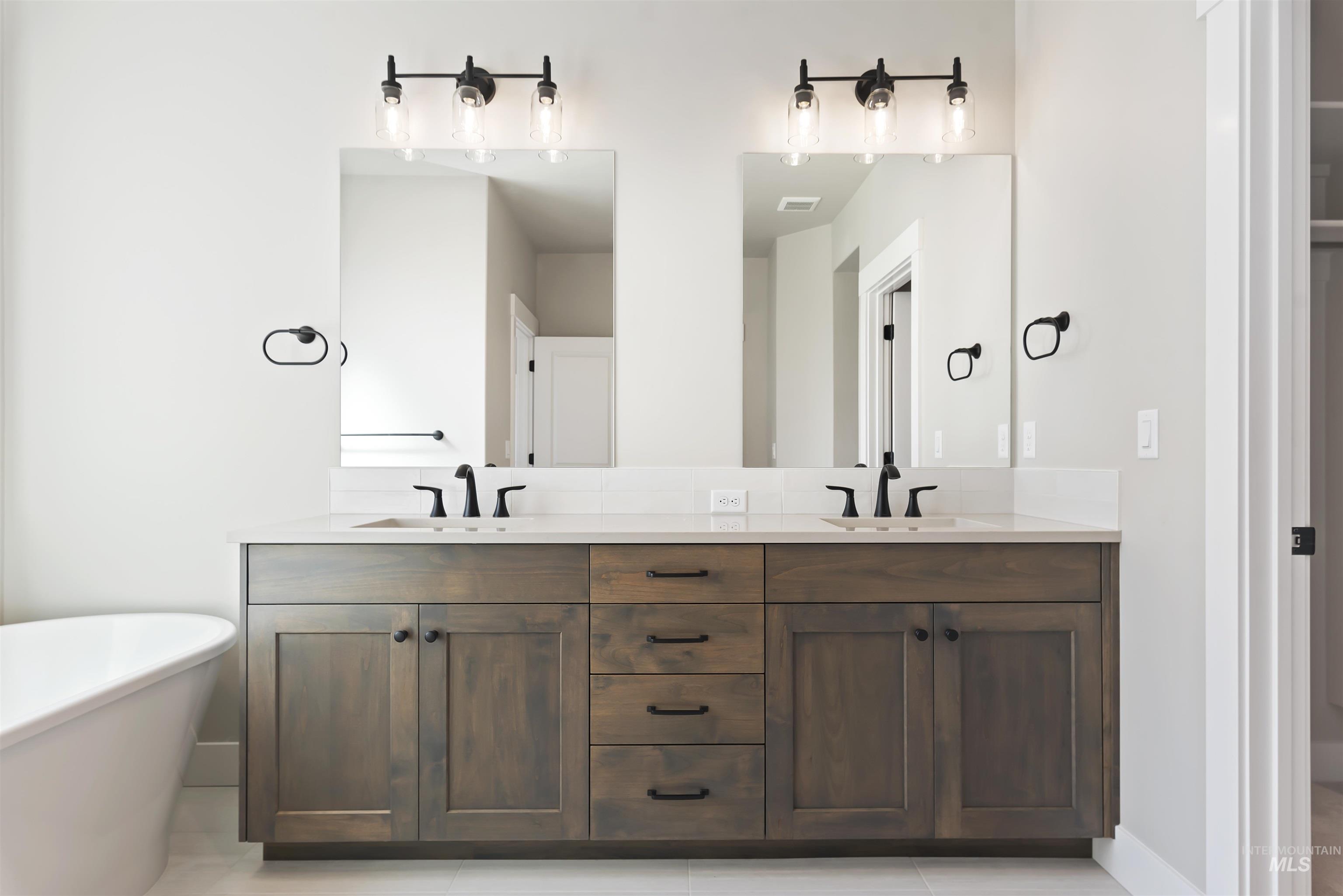Full bath featuring double vanity, a freestanding bath, and light tile patterned flooring