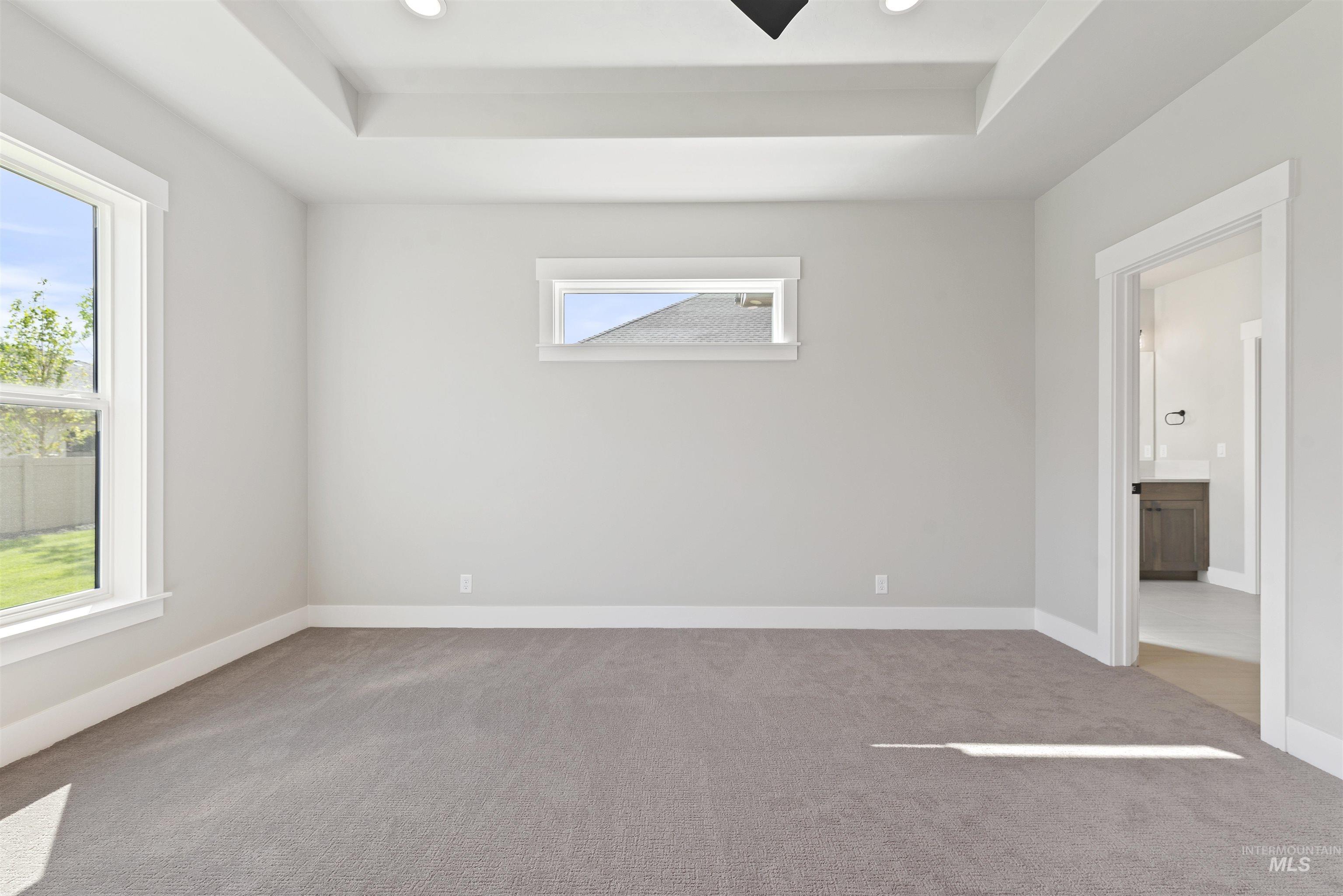 Empty room featuring light colored carpet, recessed lighting, and a raised ceiling