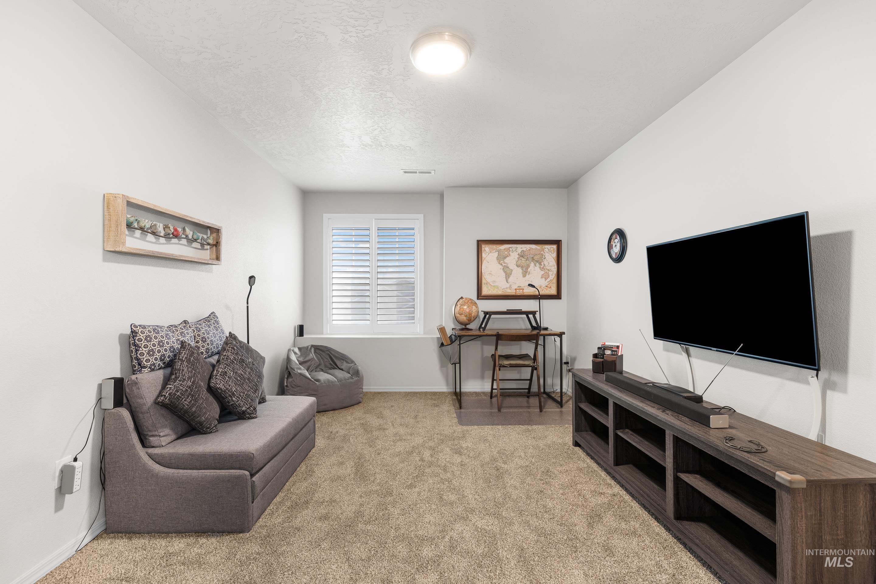 Living area featuring light carpet and a textured ceiling