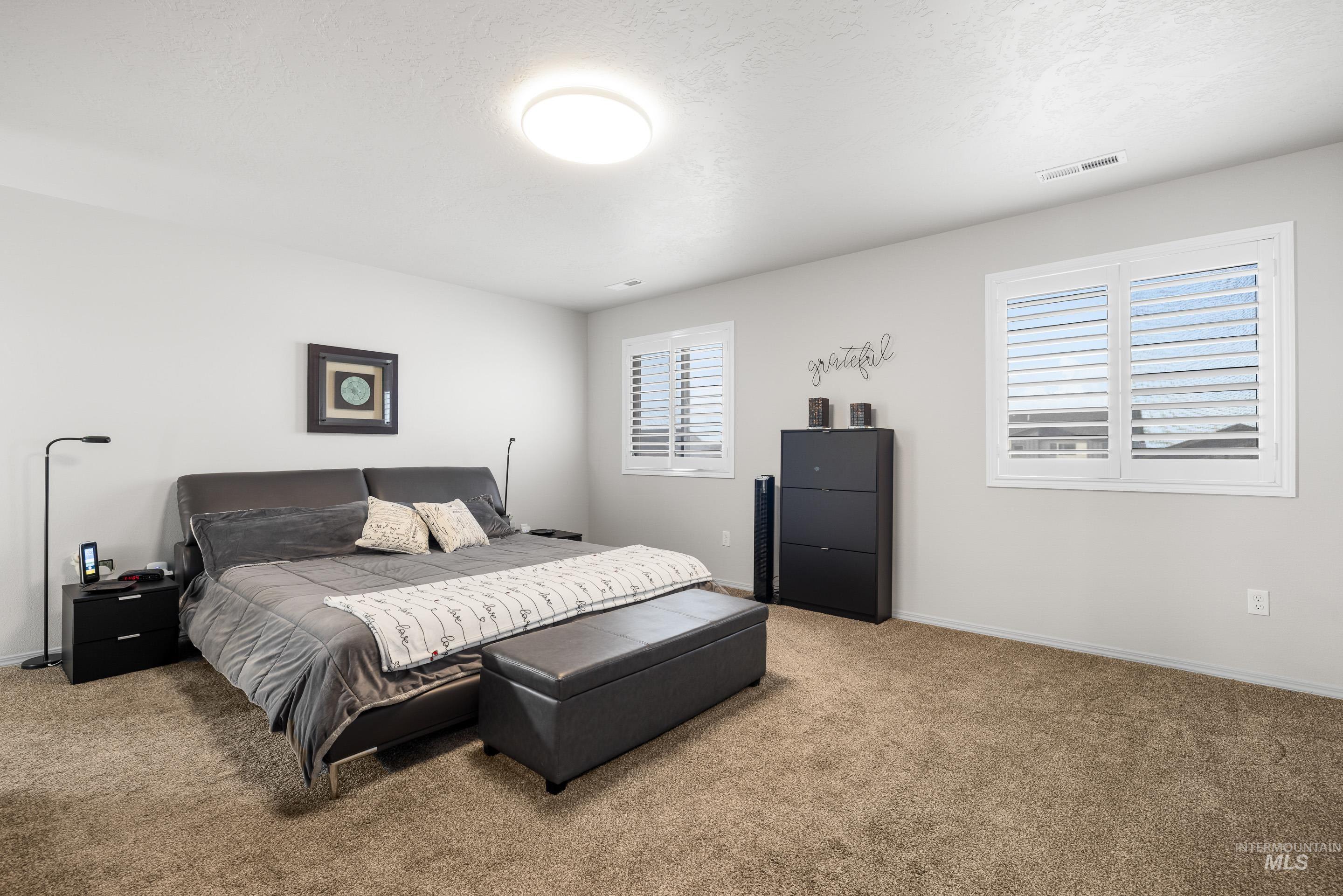Carpeted bedroom featuring baseboards and a textured ceiling