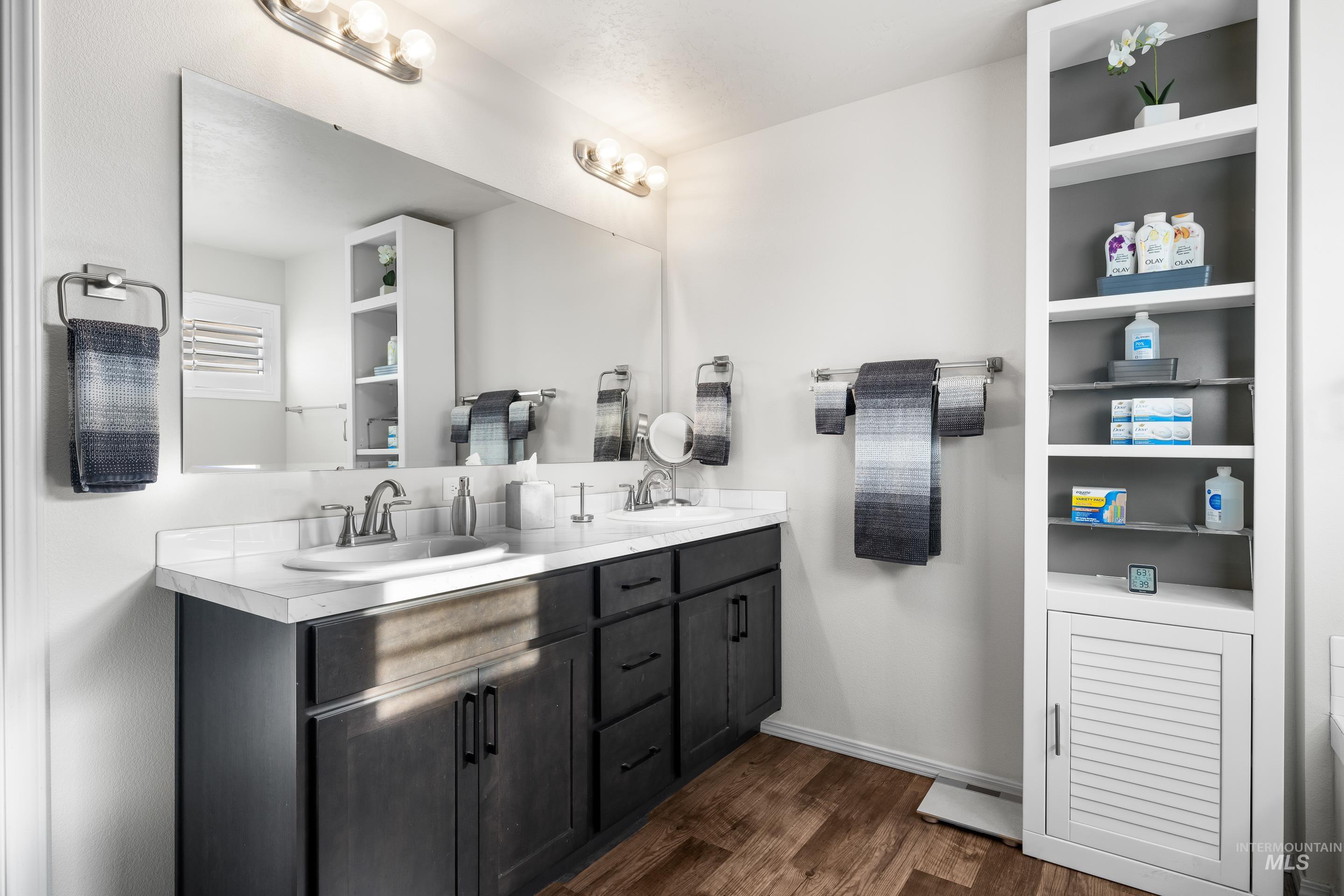 Bathroom featuring double vanity and dark wood-type flooring