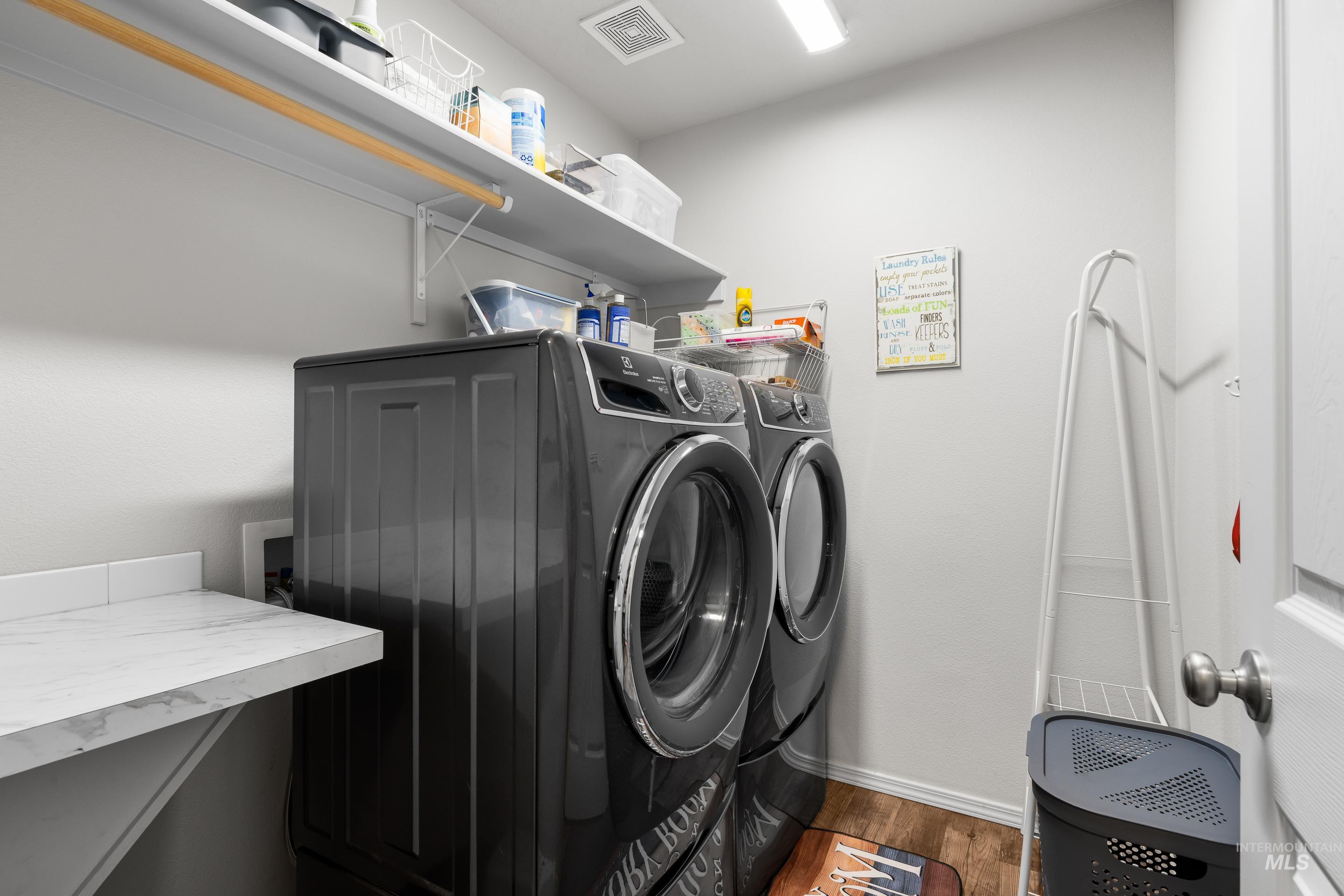 Laundry area with independent washer and dryer and wood finished floors