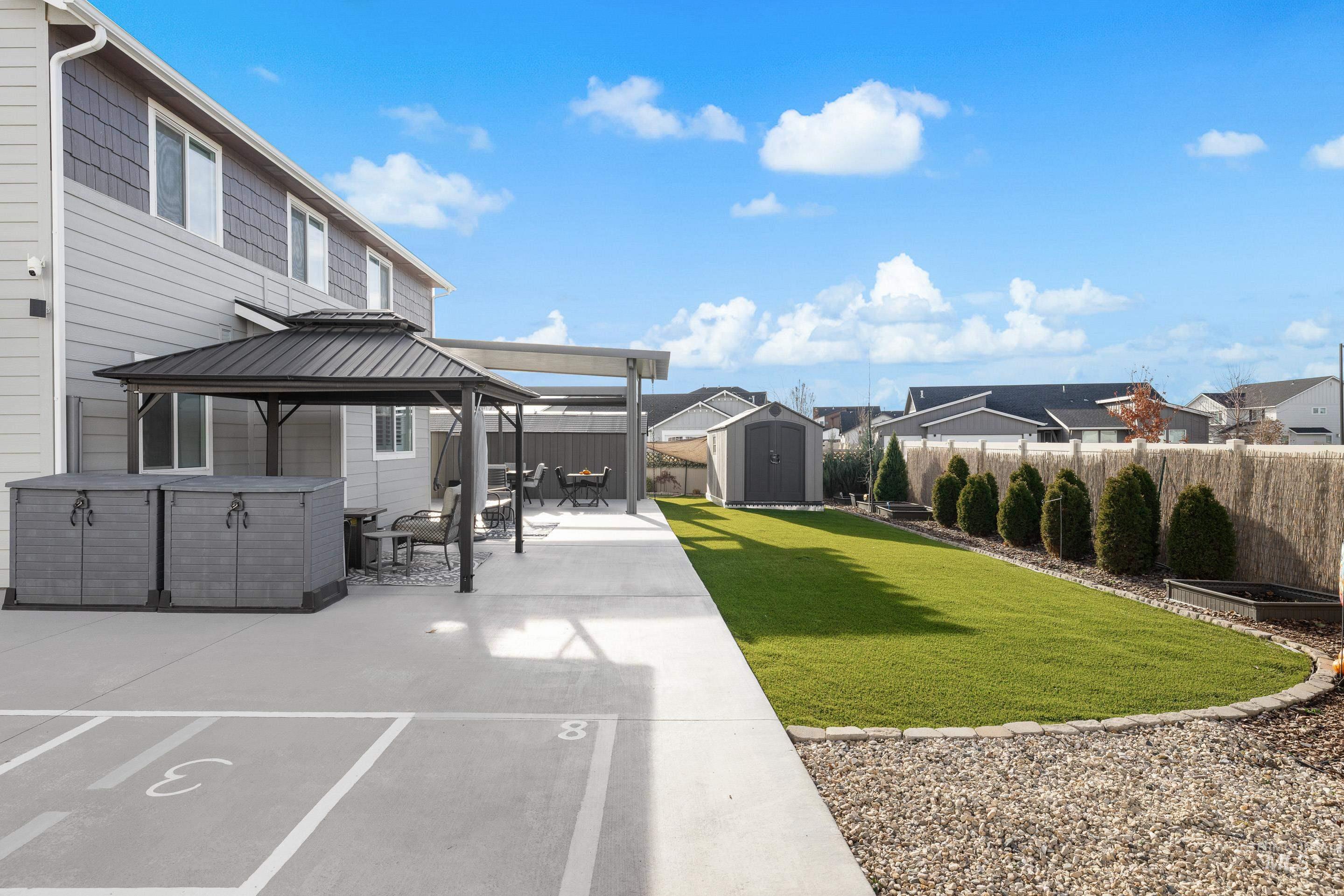 Fenced backyard with a gazebo, a storage shed, a patio area, and a jacuzzi