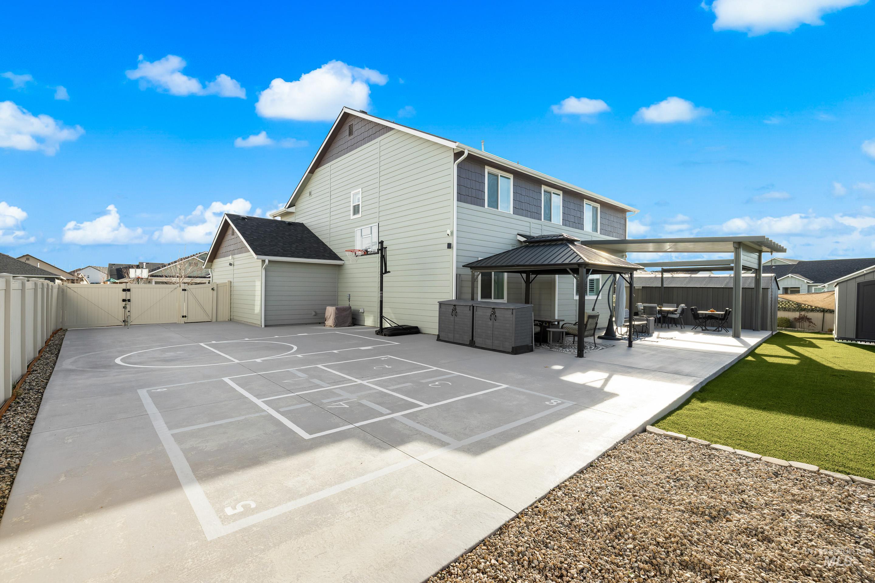 Rear view of property featuring a gazebo, a fenced backyard, a patio area, a hot tub, and a gate