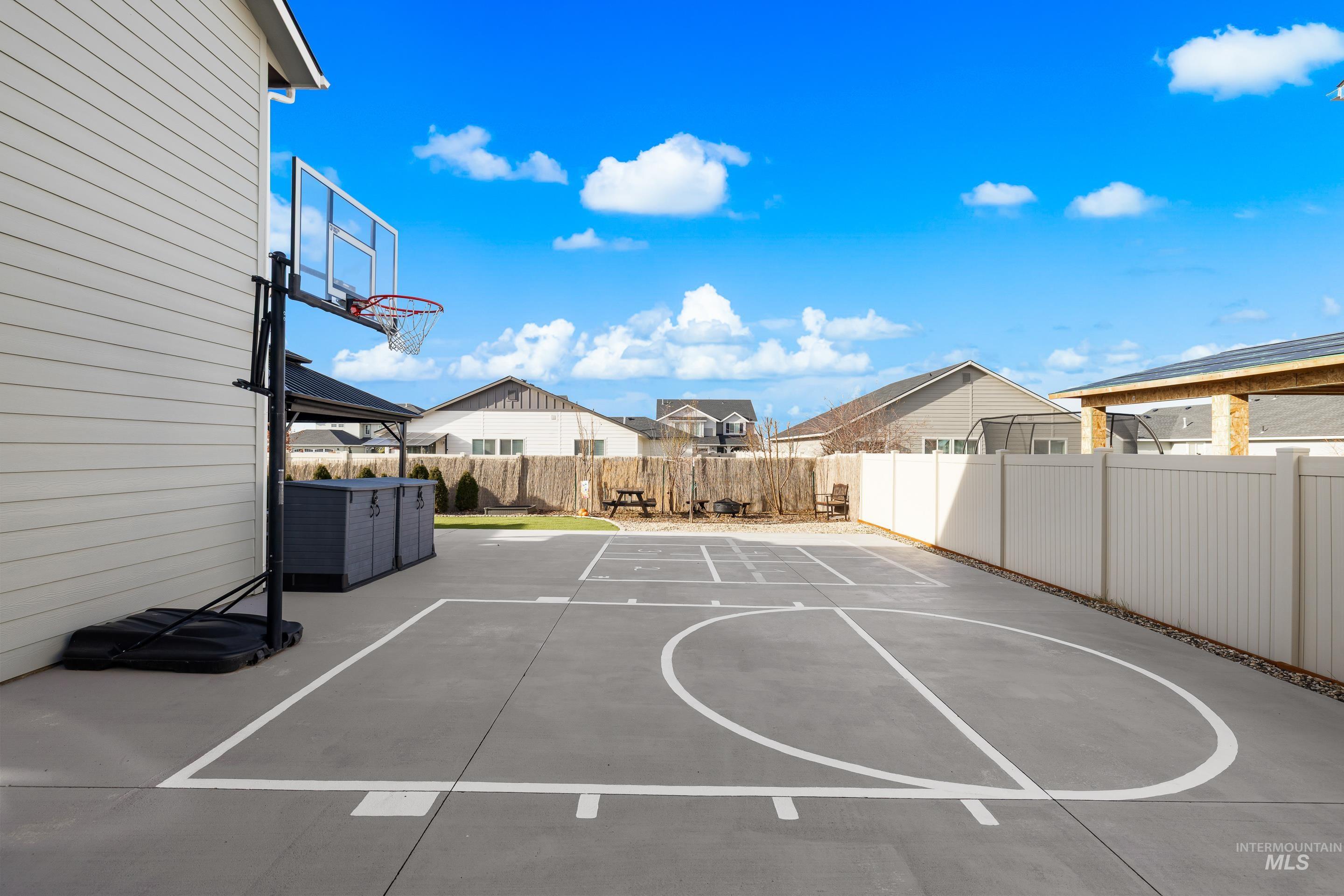 View of sport court with basketball court, a fenced backyard, a patio, and a residential view