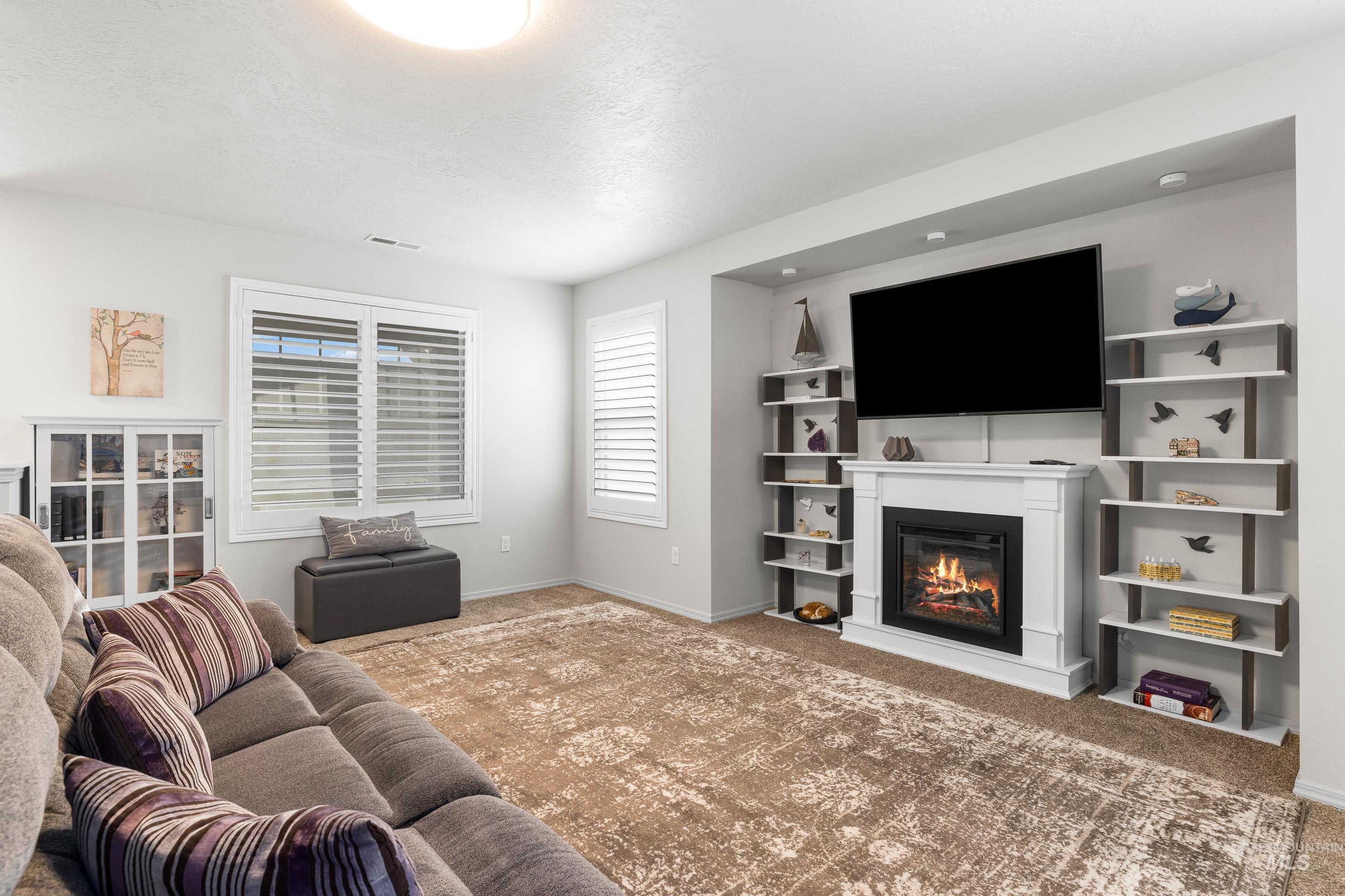 Carpeted living room with a glass covered fireplace and baseboards