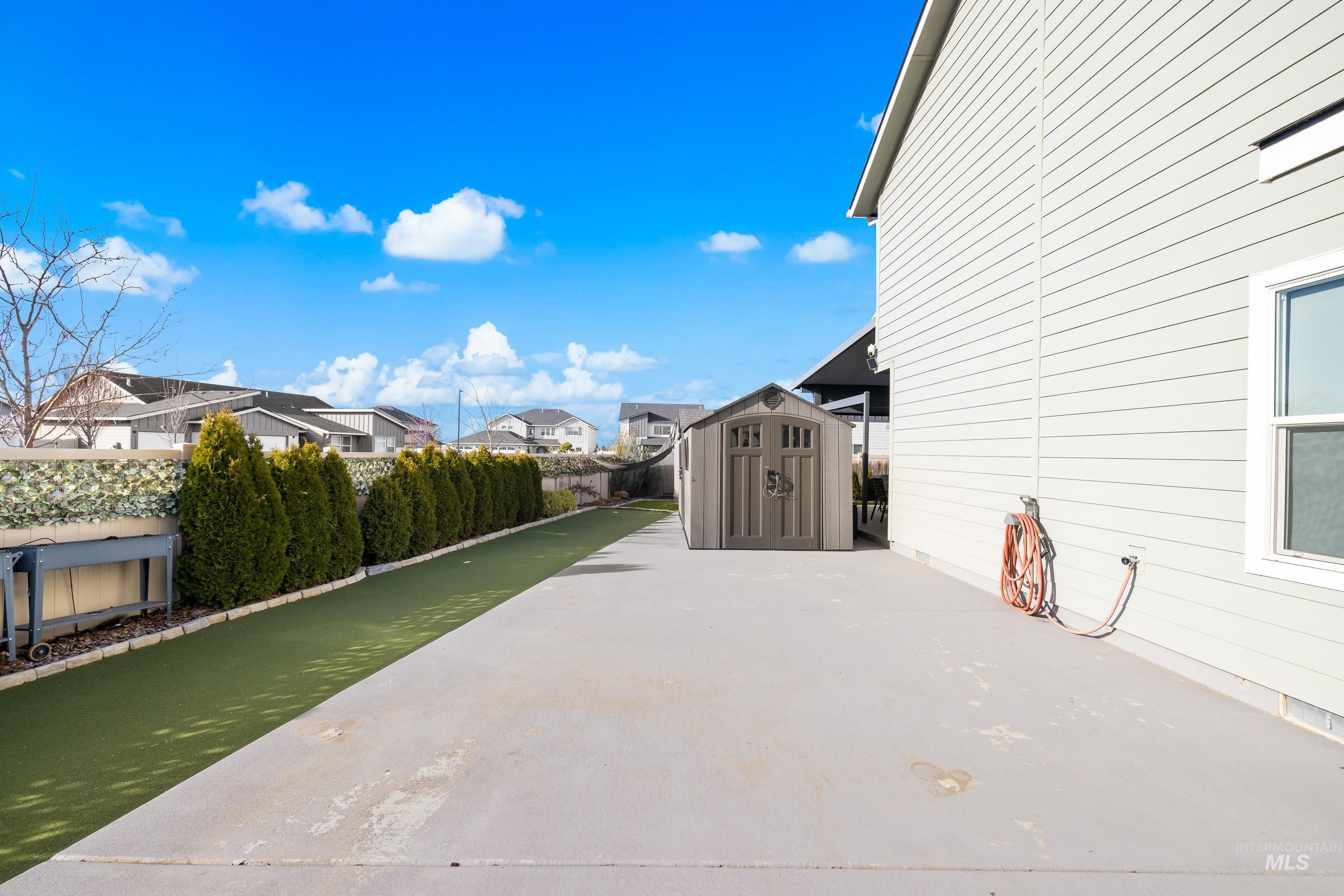 Fenced backyard featuring a storage shed and a residential view