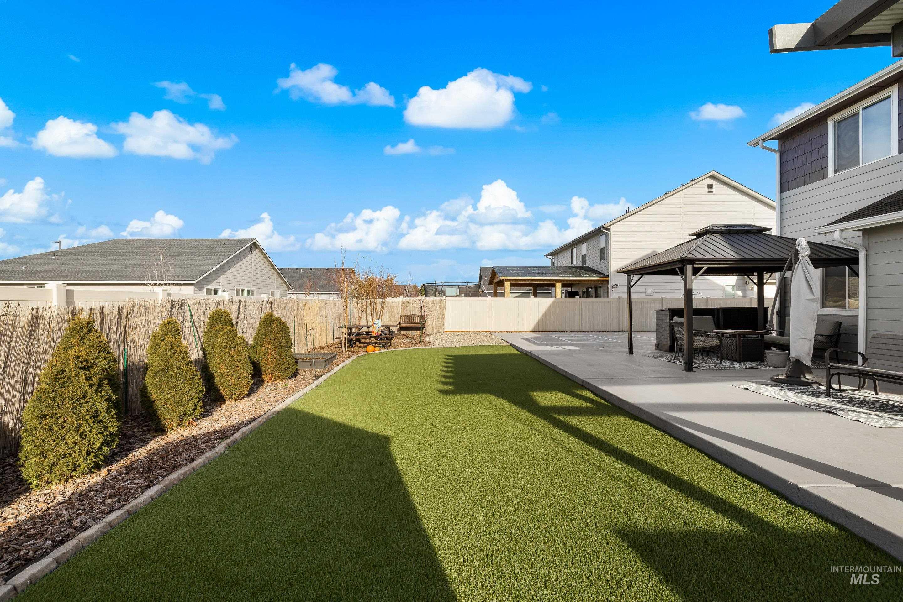 Fenced backyard featuring a gazebo and a patio area