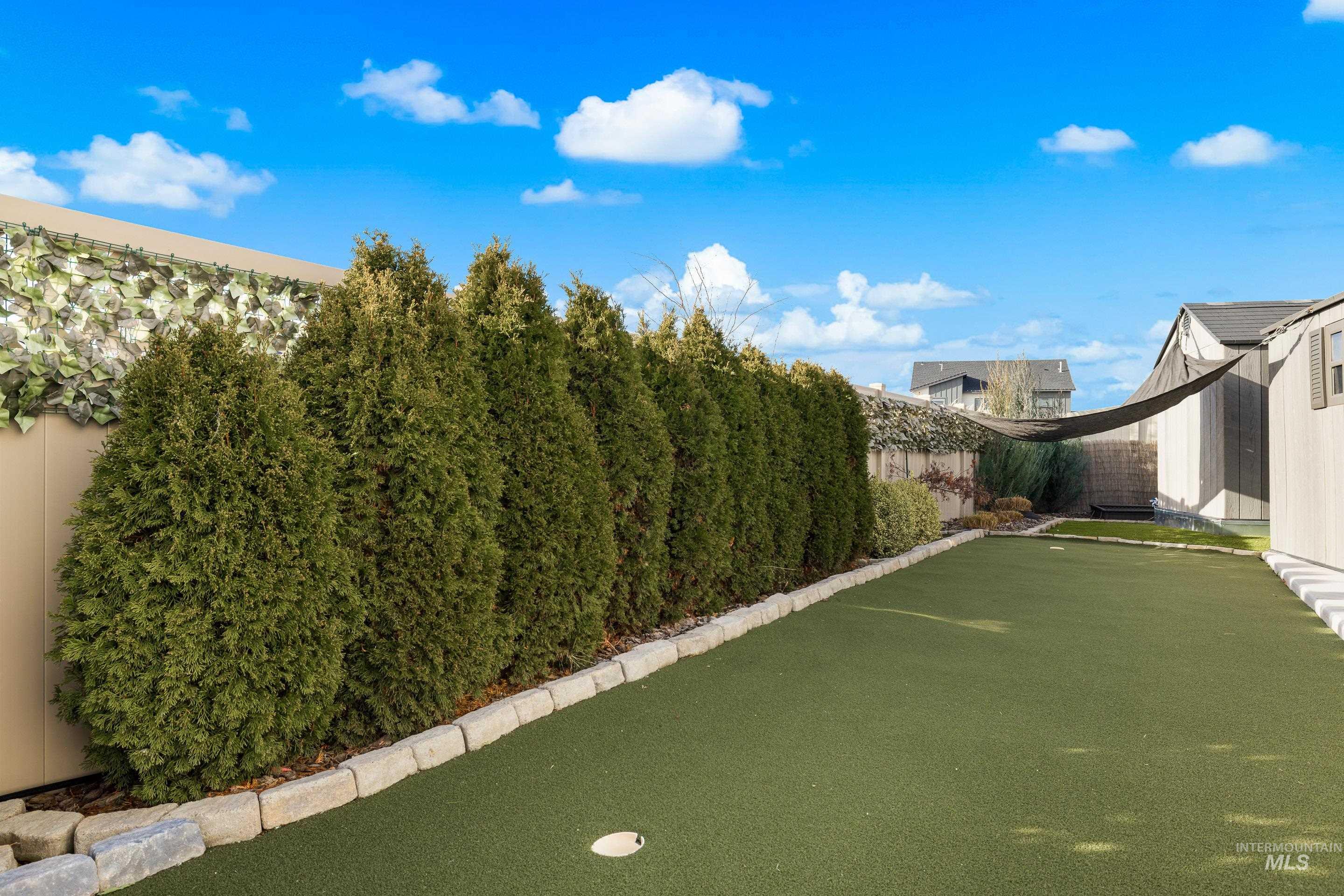 Fenced backyard with a putting area