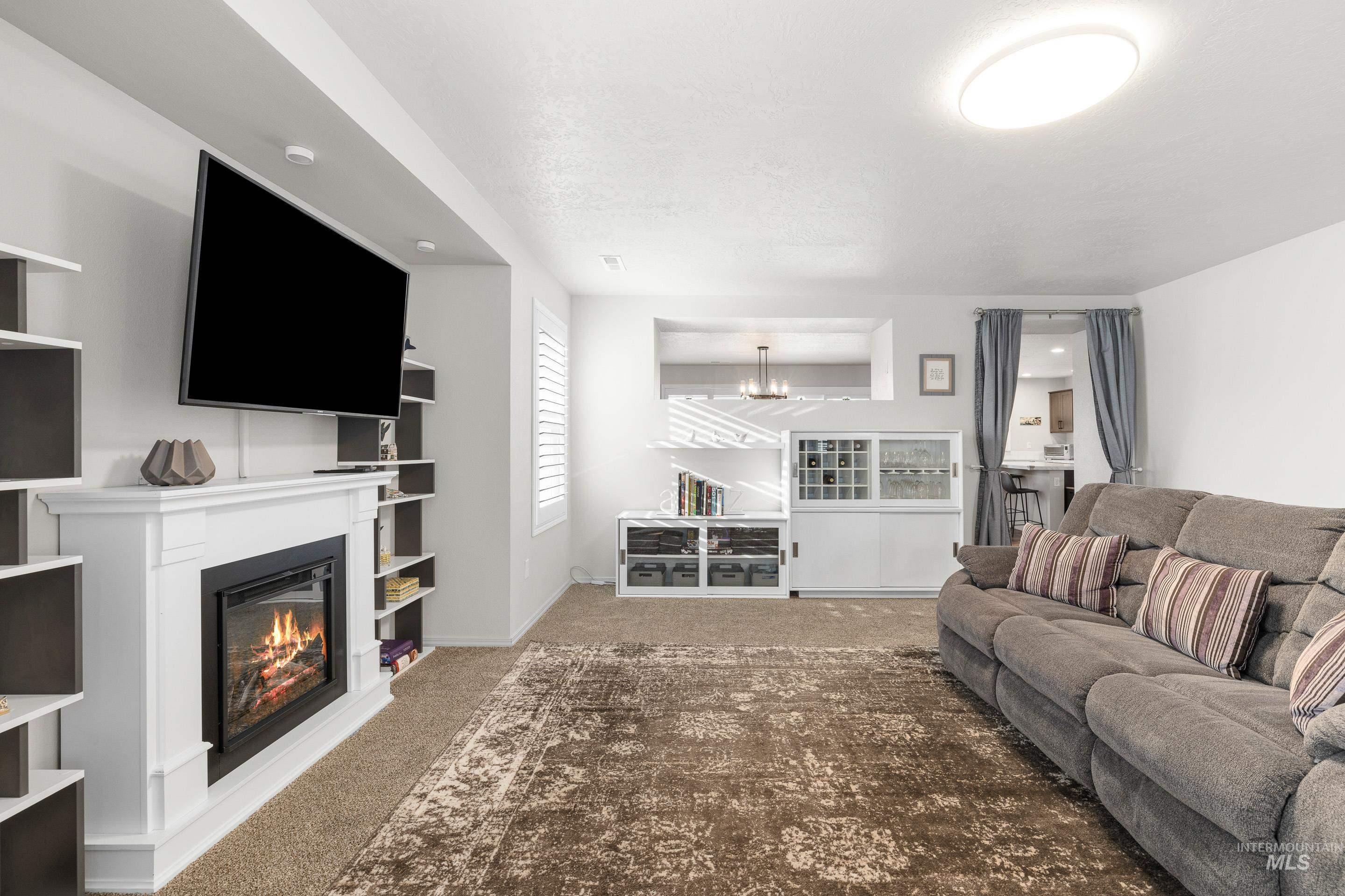Living room with carpet floors, a glass covered fireplace, and a chandelier