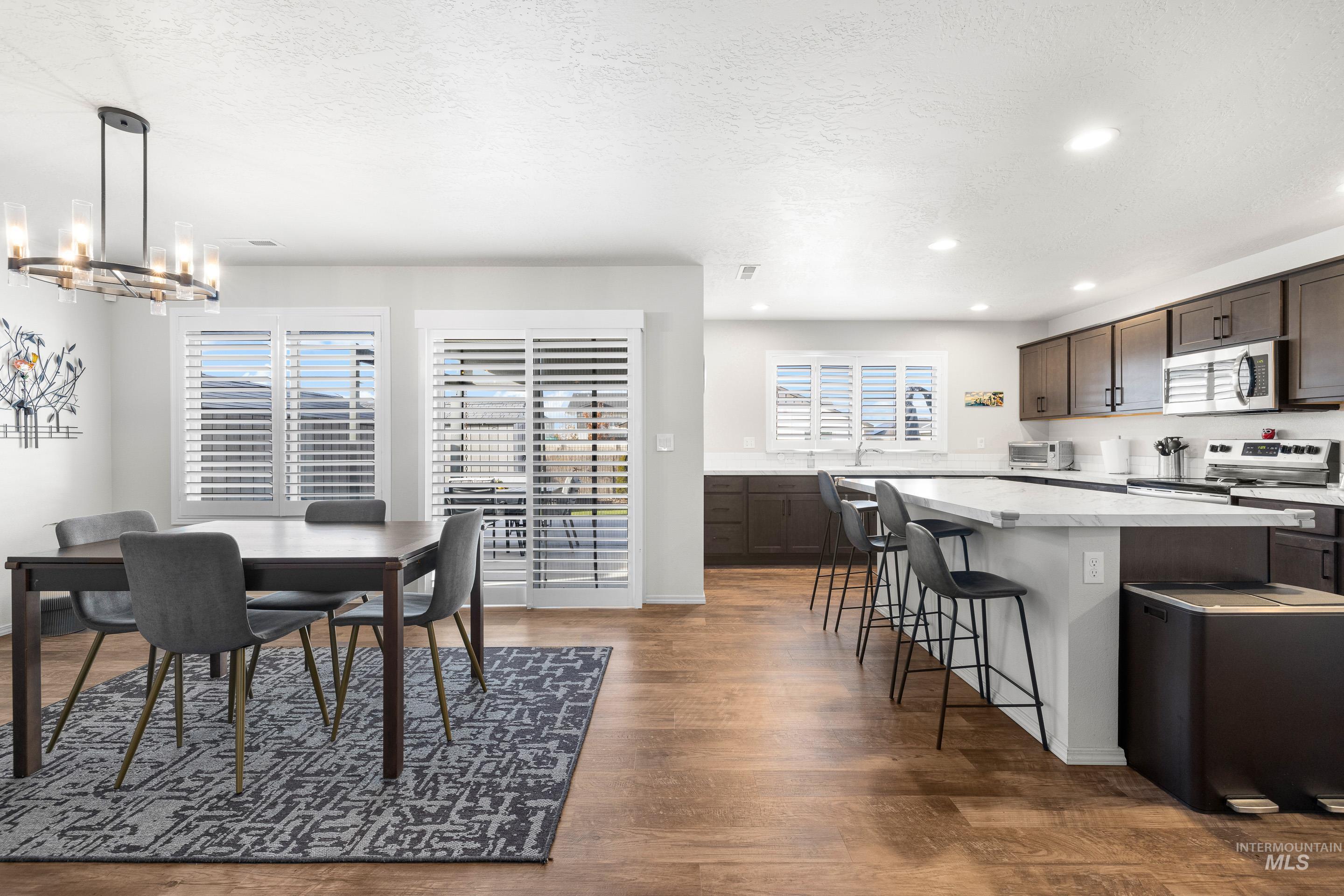 Dining area featuring a textured ceiling, dark wood-style floors, a chandelier, and recessed lighting