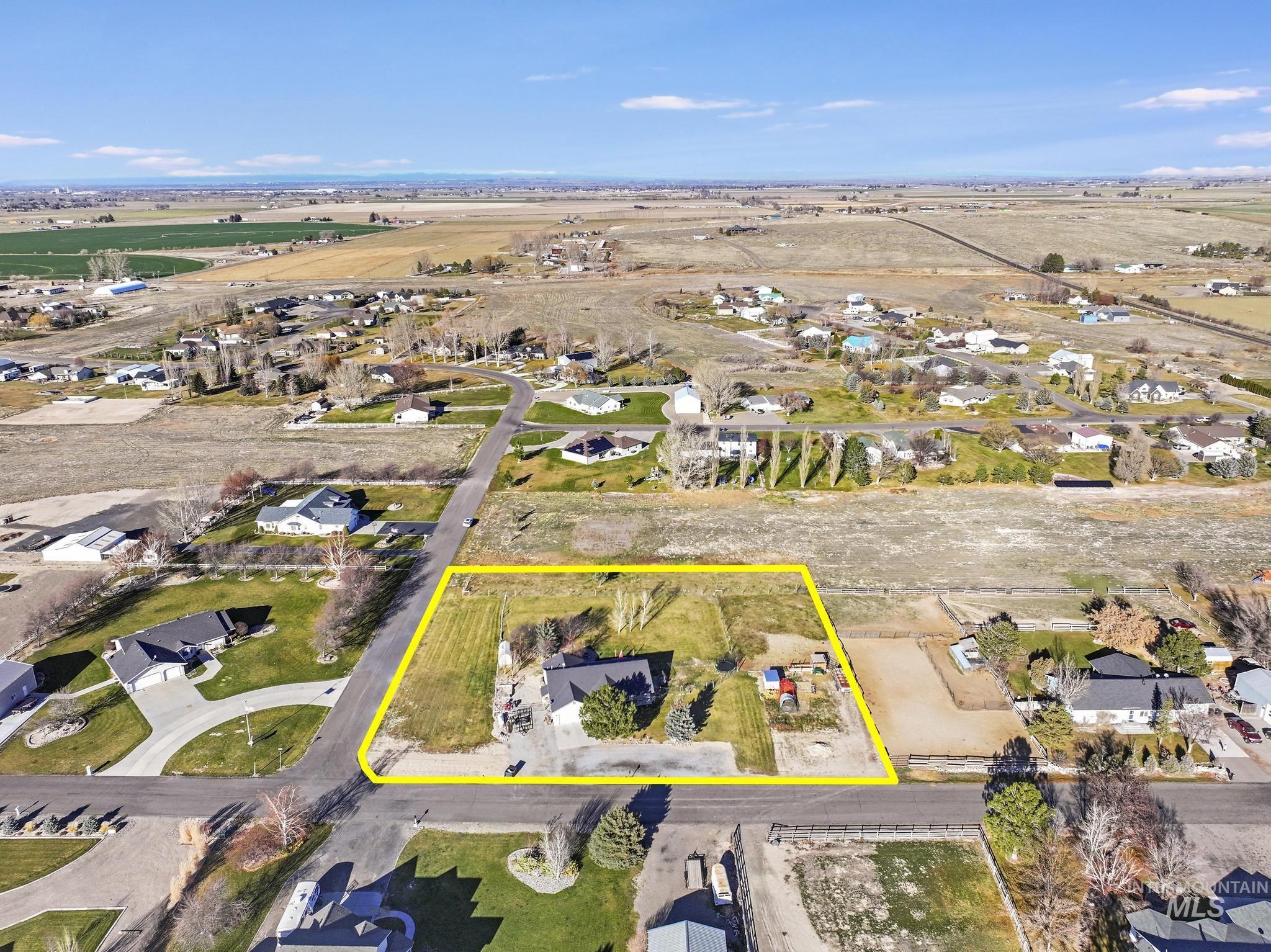 Aerial view of sparsely populated area featuring property boundaries highlighted and nearby suburban area