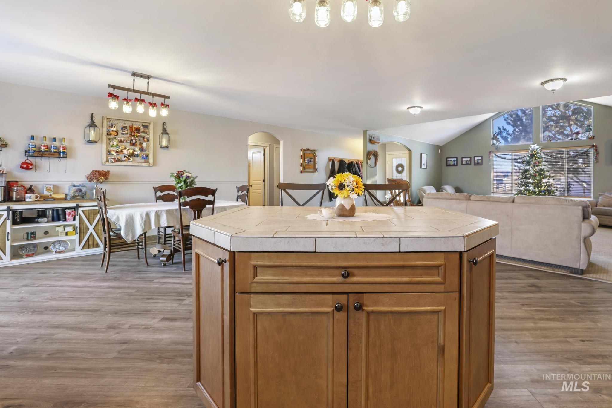 Kitchen featuring brown cabinets, open floor plan, tile countertops, a center island, and vaulted ceiling