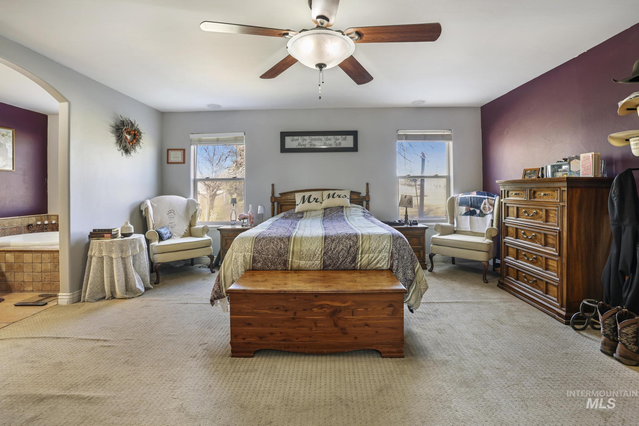 Bedroom with ceiling fan, carpet flooring, and arched walkways