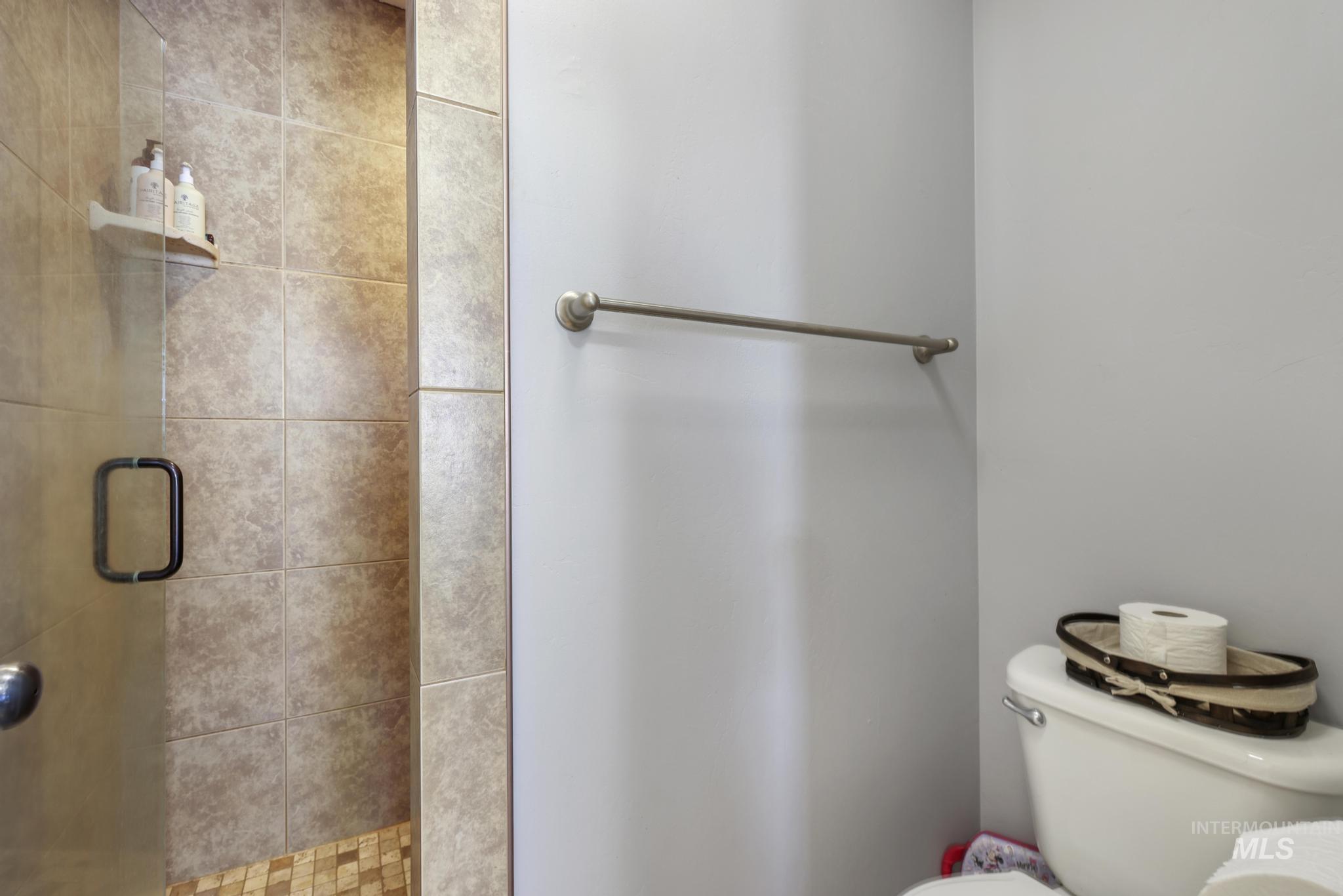 Full bath featuring a shower stall and toilet