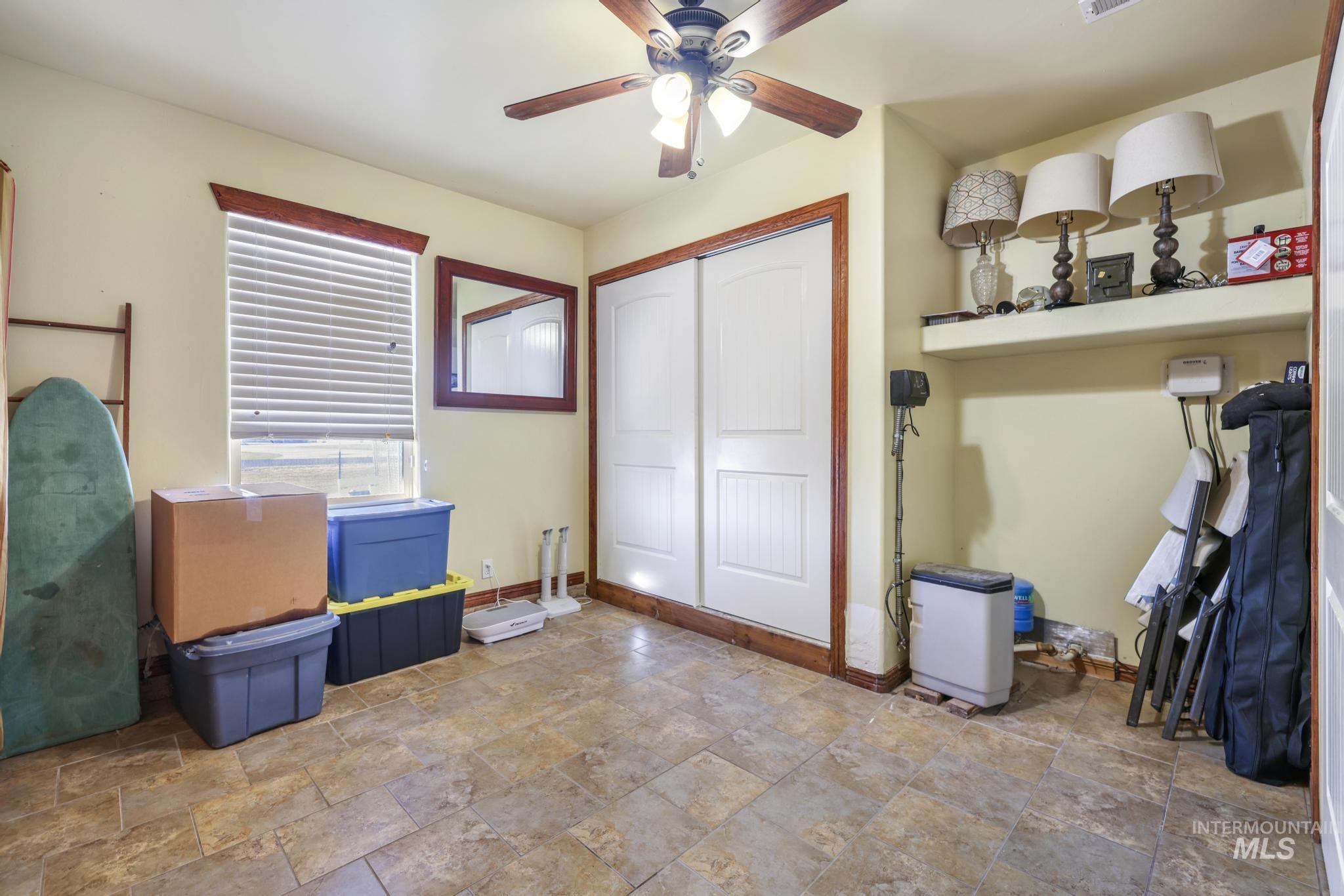 Bedroom with stone tile flooring, a ceiling fan, and a closet