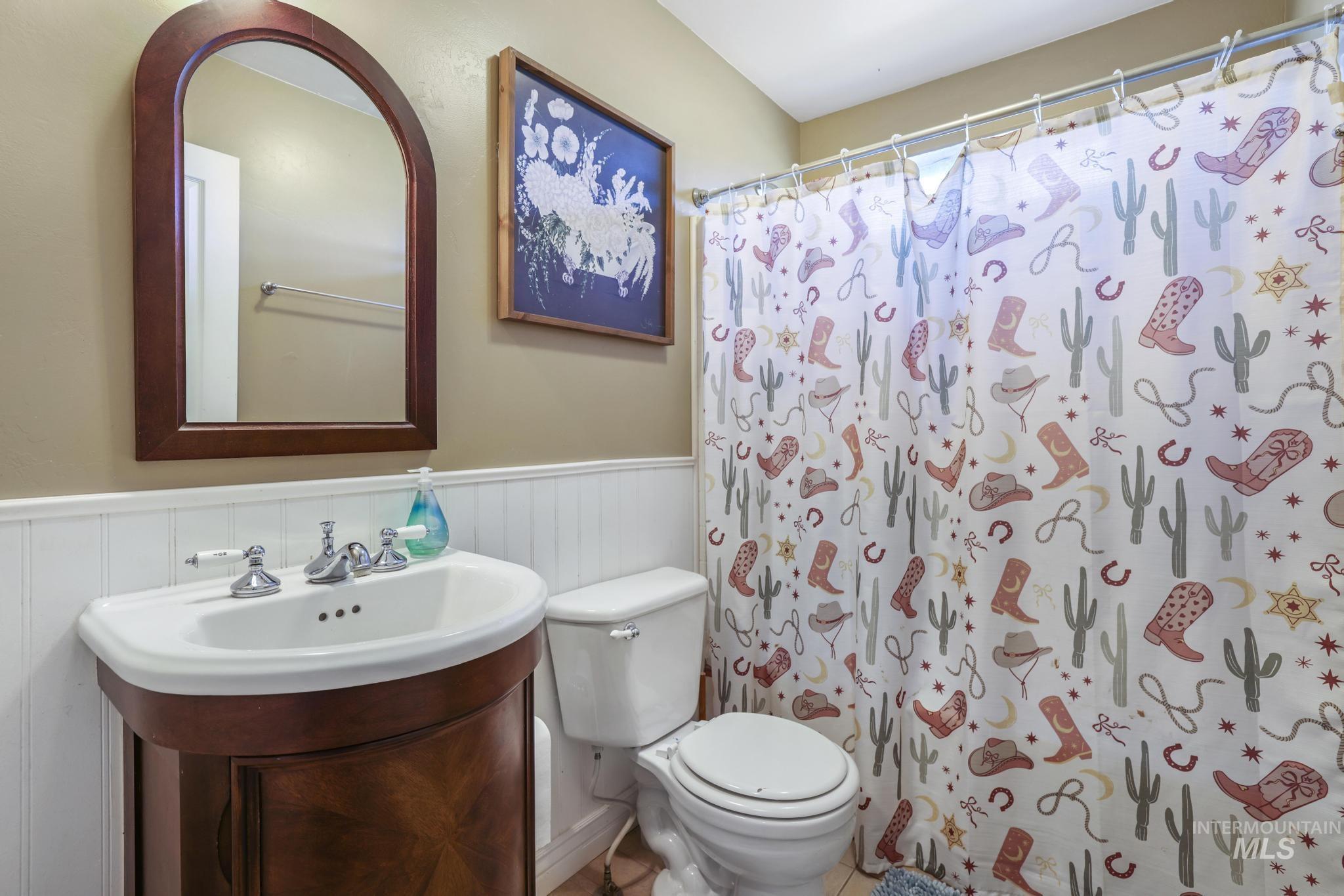 Full bathroom with wainscoting, curtained shower, and vanity