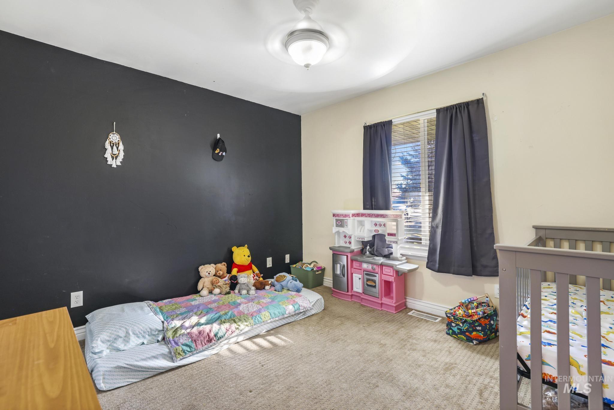 Bedroom featuring carpet, an accent wall, and a nursery area