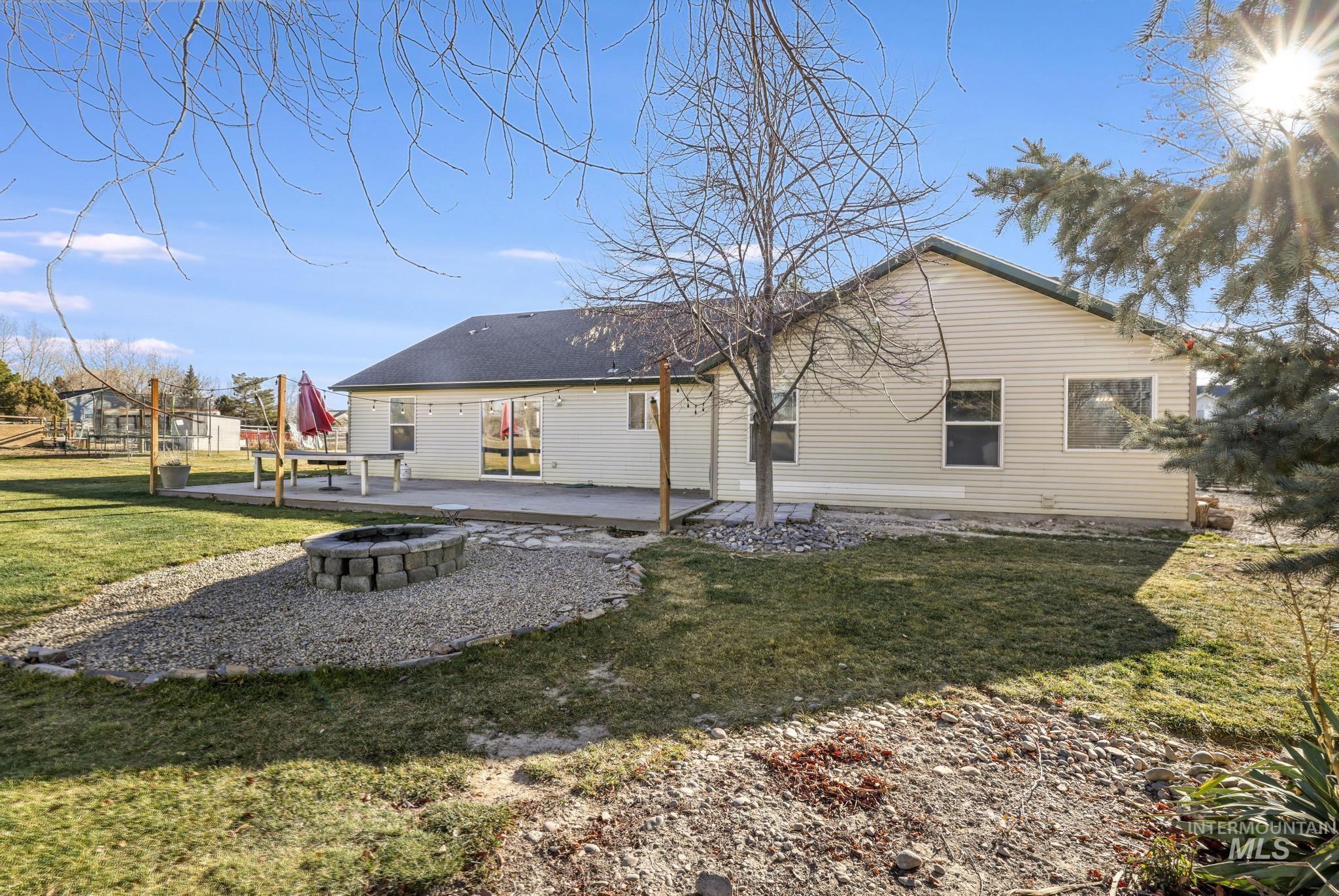Rear view of property featuring a fire pit, a yard, and a patio
