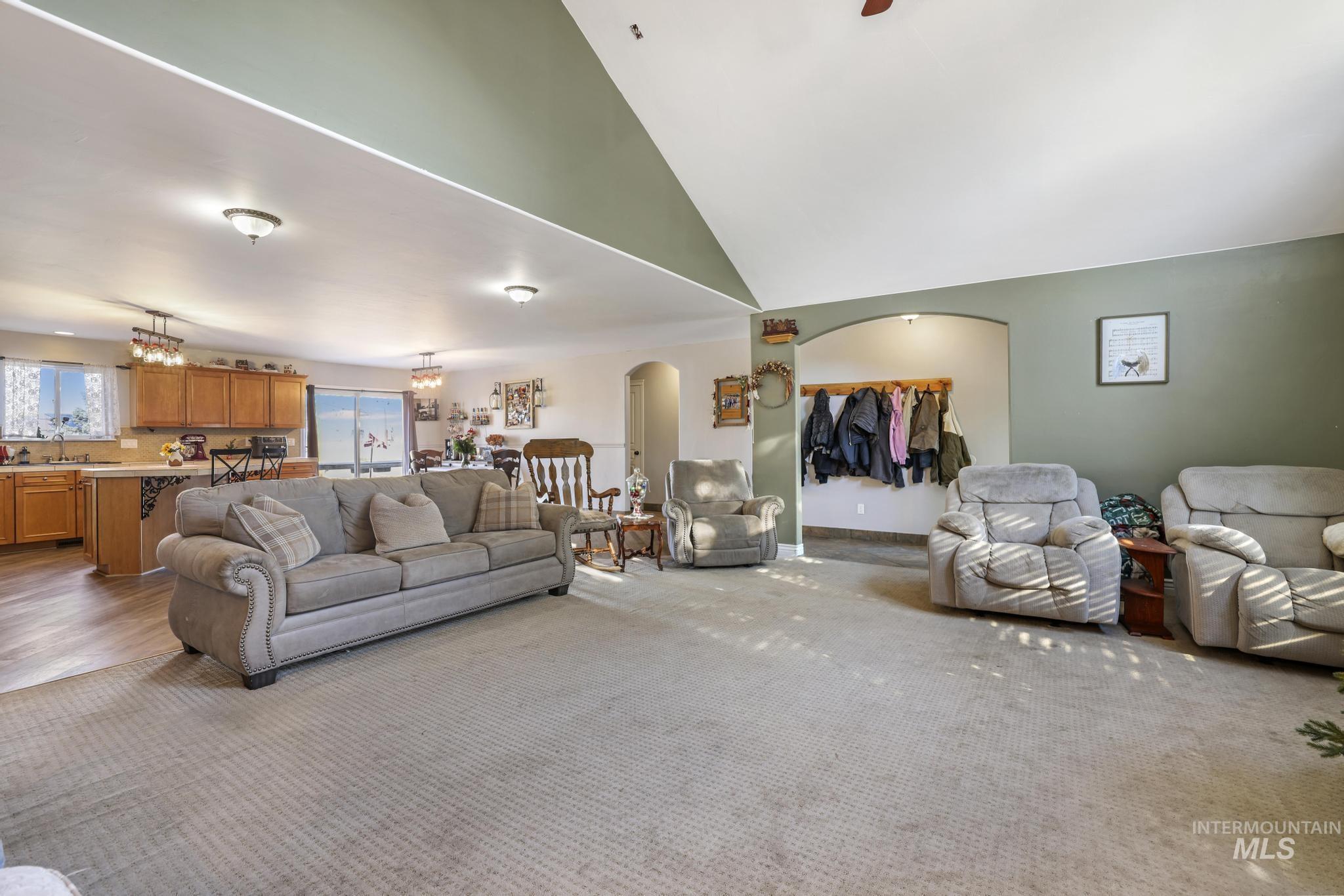 Living area featuring arched walkways, a chandelier, high vaulted ceiling, and a ceiling fan