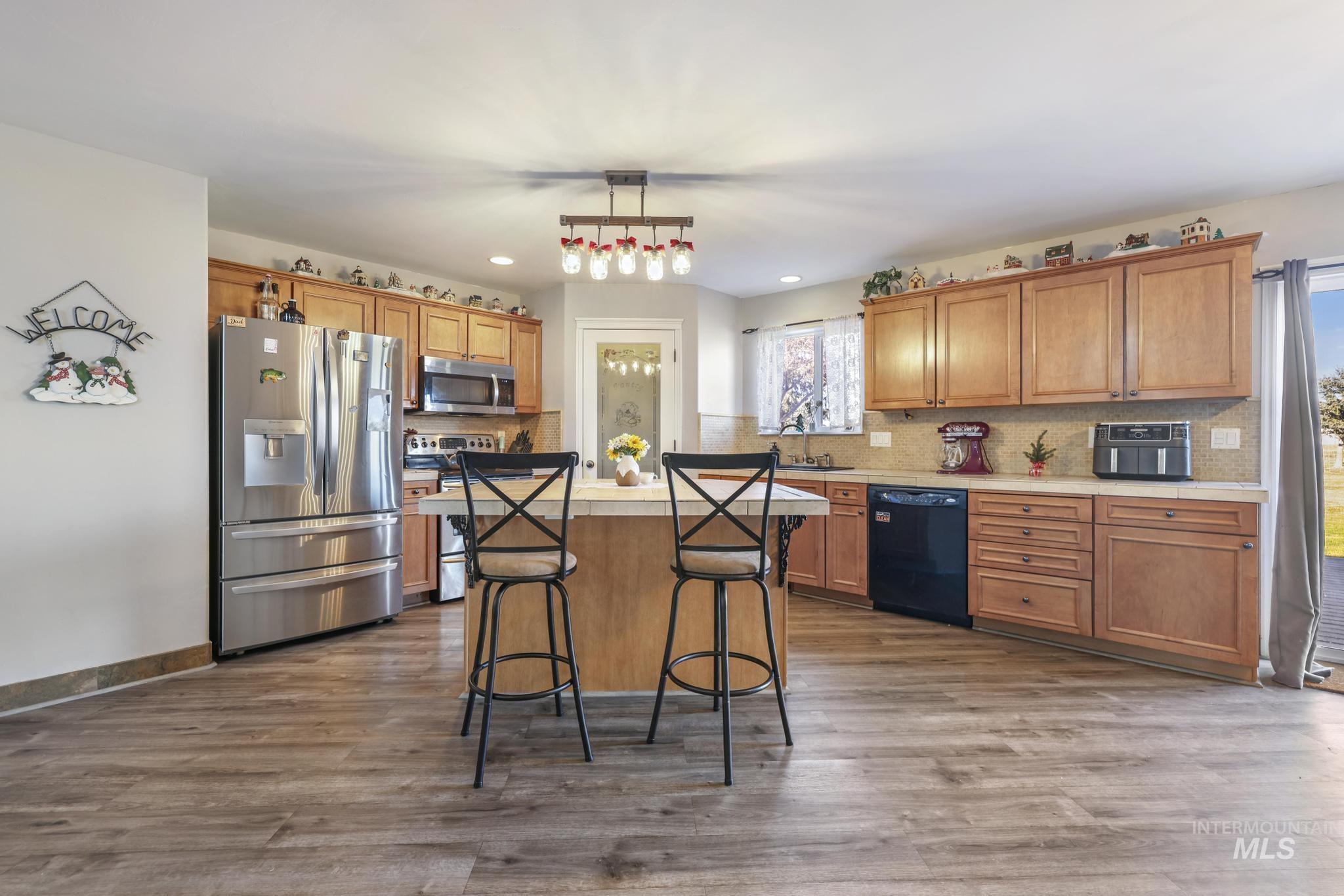 Kitchen featuring stainless steel appliances, decorative backsplash, and brown cabinets