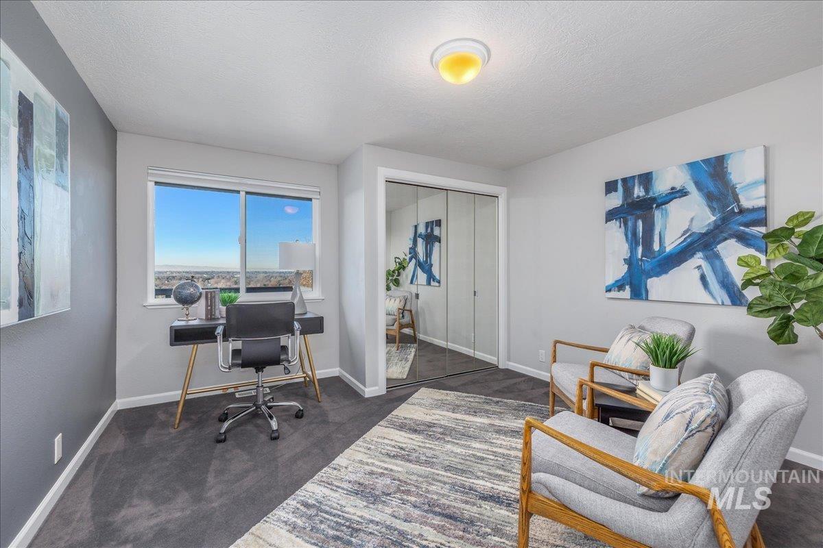 Office area featuring a textured ceiling and dark colored carpet
