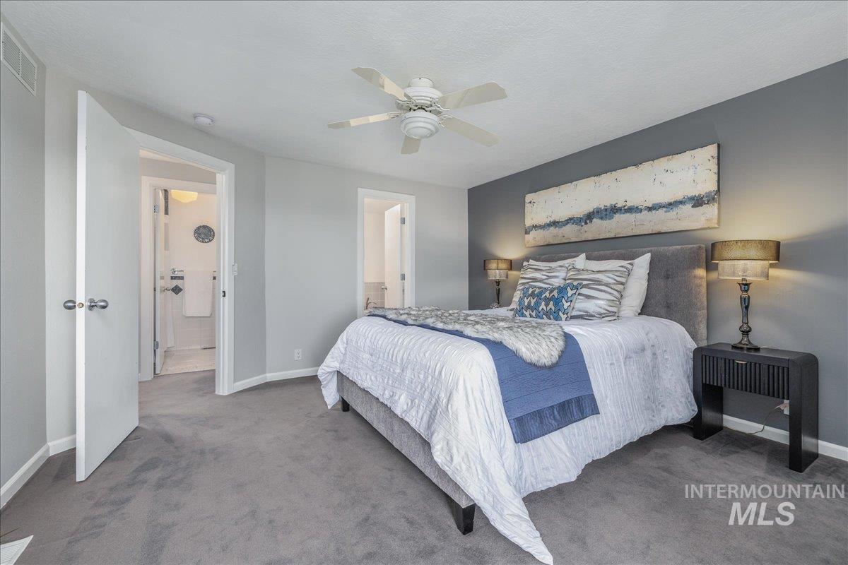 Carpeted bedroom featuring ceiling fan and ensuite bathroom