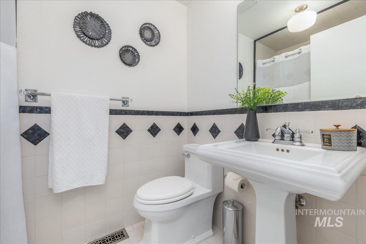 Bathroom with tile walls, a shower with shower curtain, a wainscoted wall, and tile patterned floors