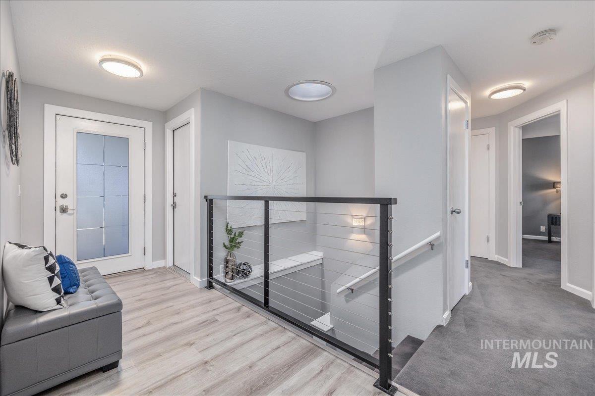 Hallway with an upstairs landing and light wood-style flooring