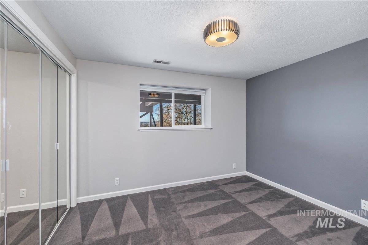 Unfurnished bedroom with a closet, a textured ceiling, and dark colored carpet