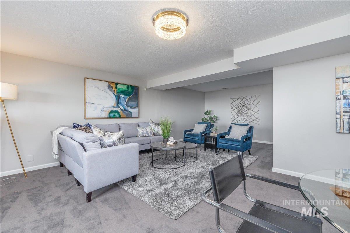 Carpeted living area featuring a textured ceiling and baseboards