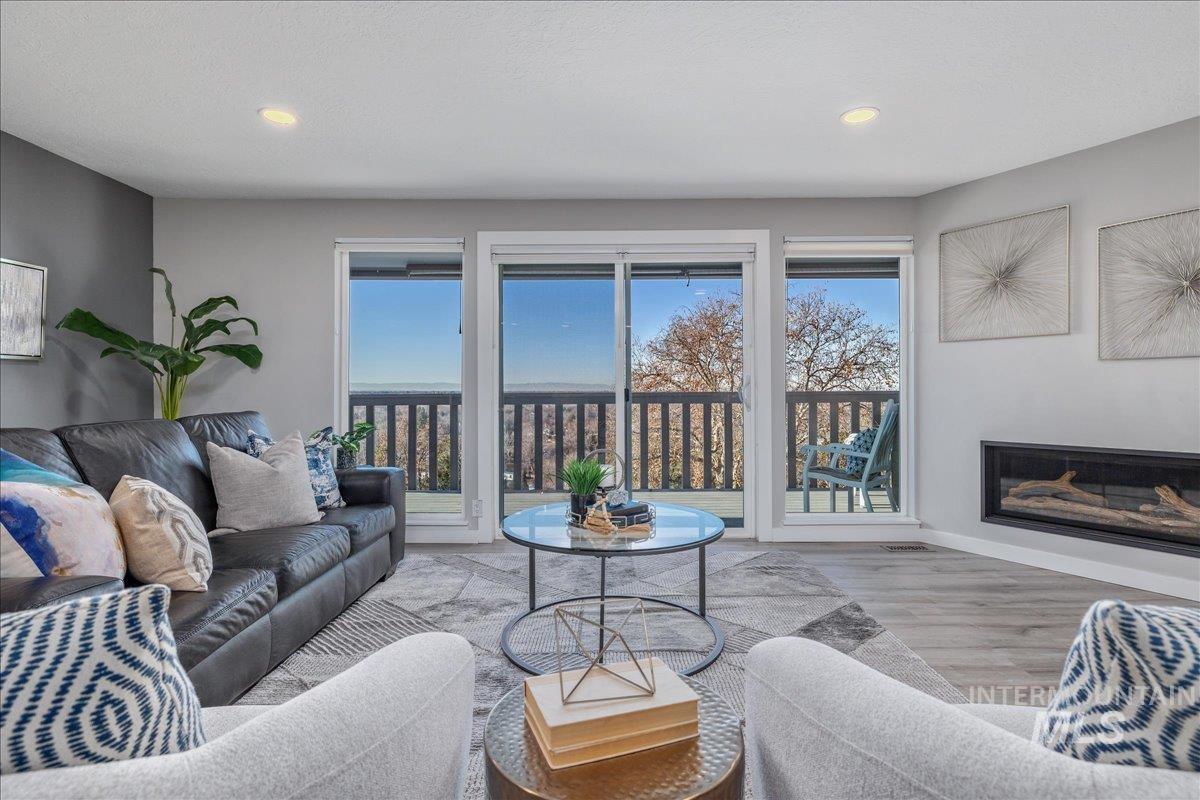 Living area featuring a glass covered fireplace, wood finished floors, and recessed lighting