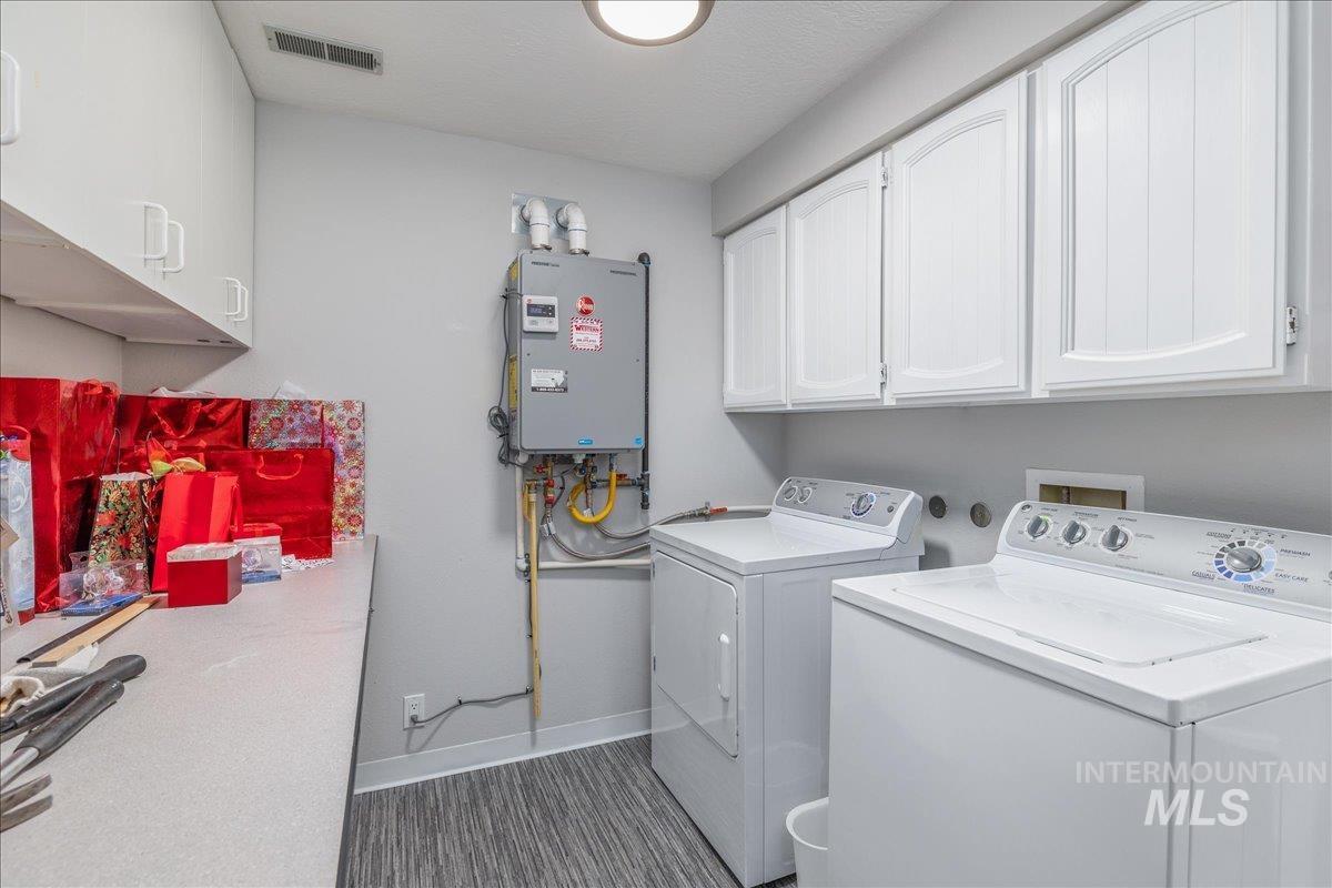 Washroom with cabinet space, separate washer and dryer, and tankless water heater