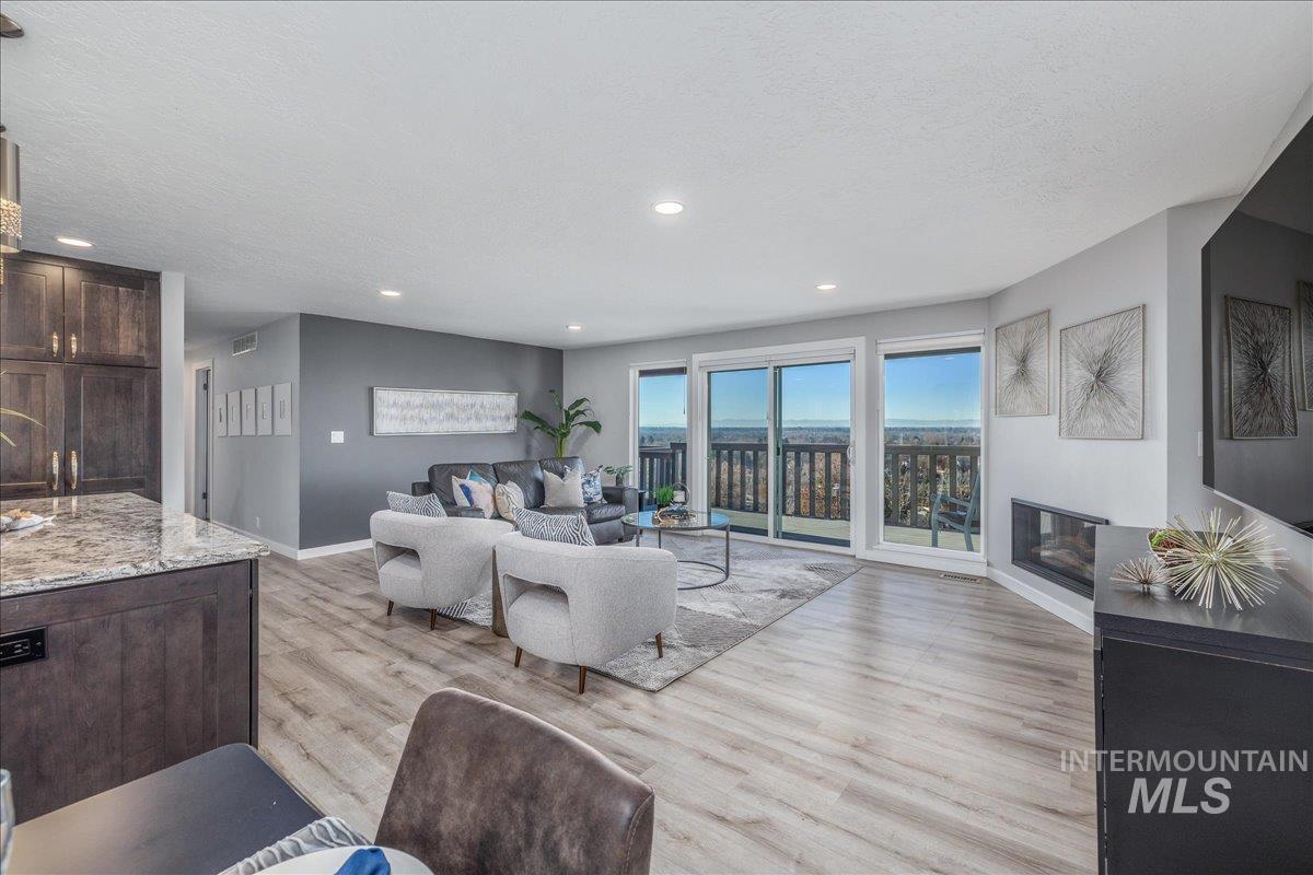 Living area with a glass covered fireplace, light wood-style flooring, a textured ceiling, and recessed lighting
