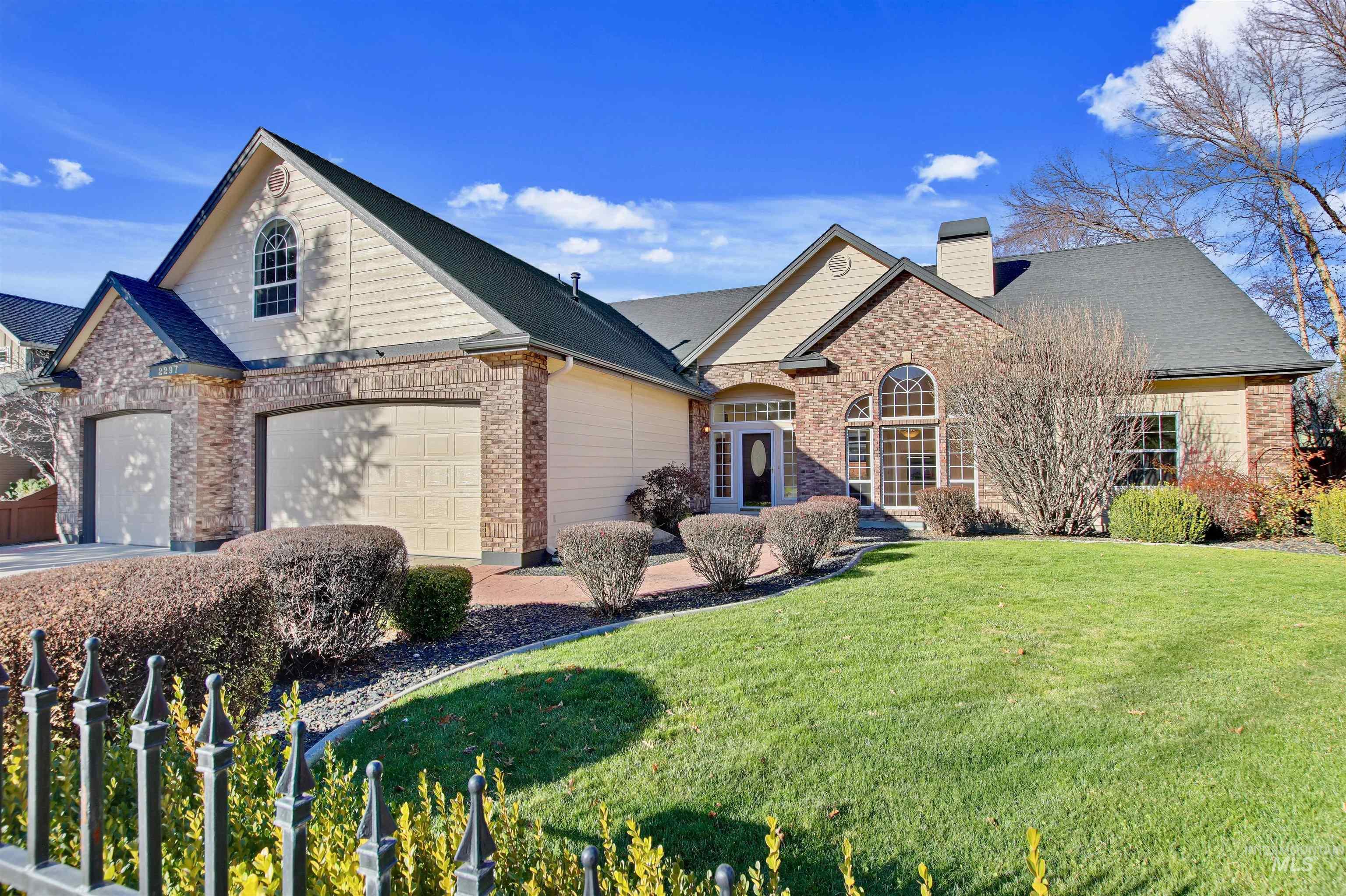 View of front facade featuring brick siding, a chimney, a front lawn, and a garage
